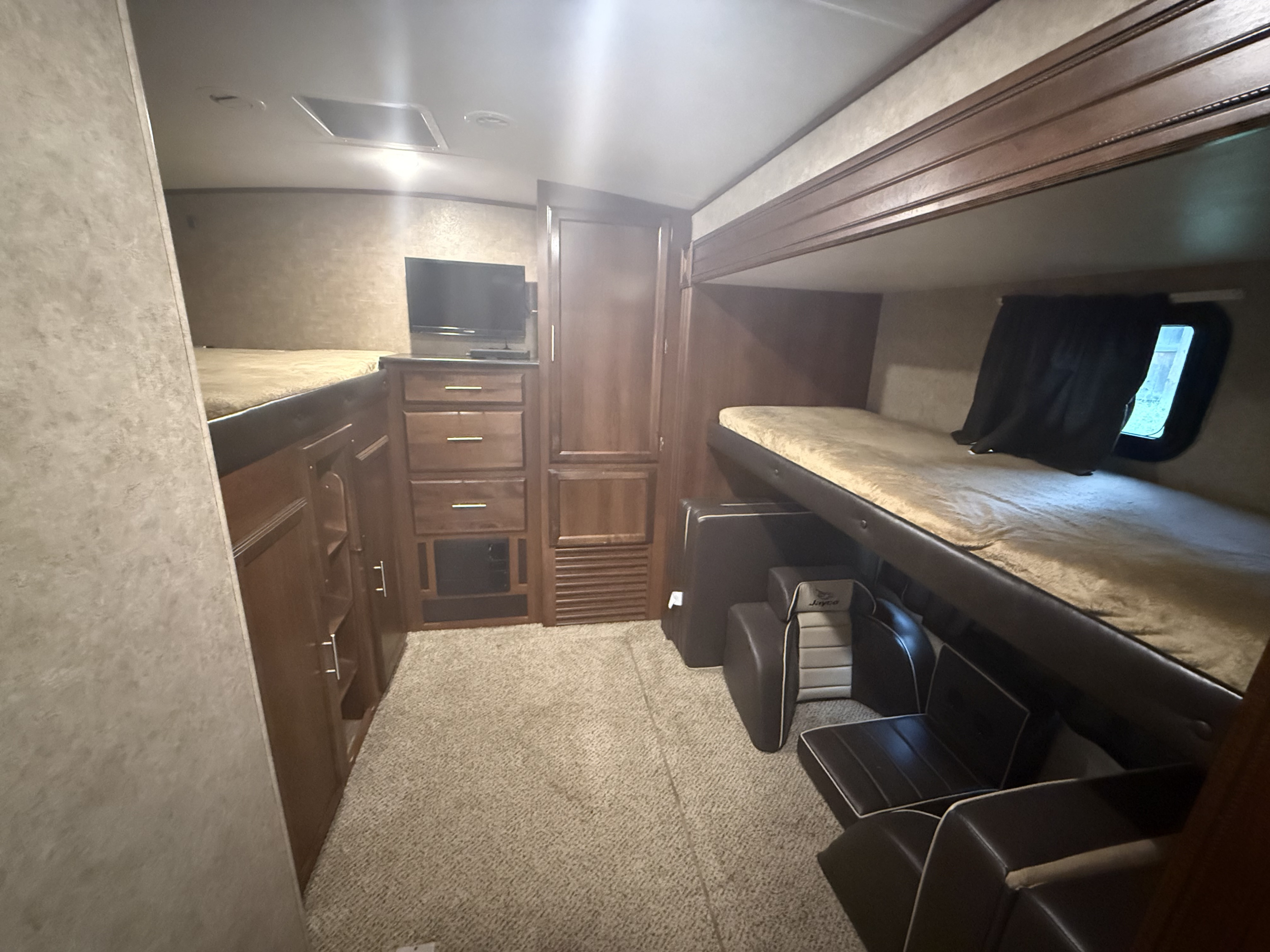 RV rental interior: A bunkhouse with two bunk beds, a TV, wood cabinetry, and flexible seating in a camper.. Jayco Eagle 2016