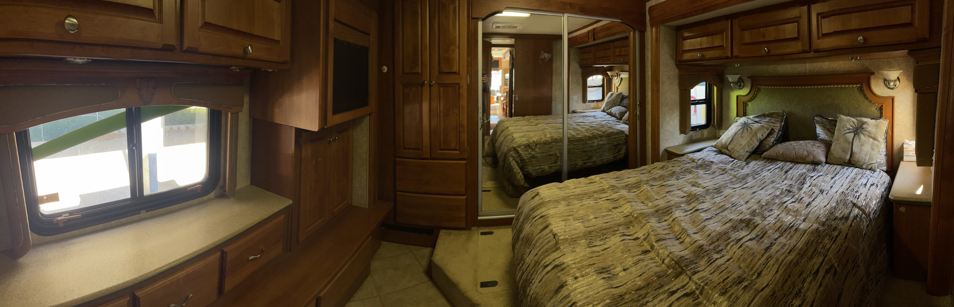 Explore this cozy RV rental bedroom interior, showcasing a comfy bed, wooden cabinets, and a large mirrored closet.. Monaco Diplomat 2006