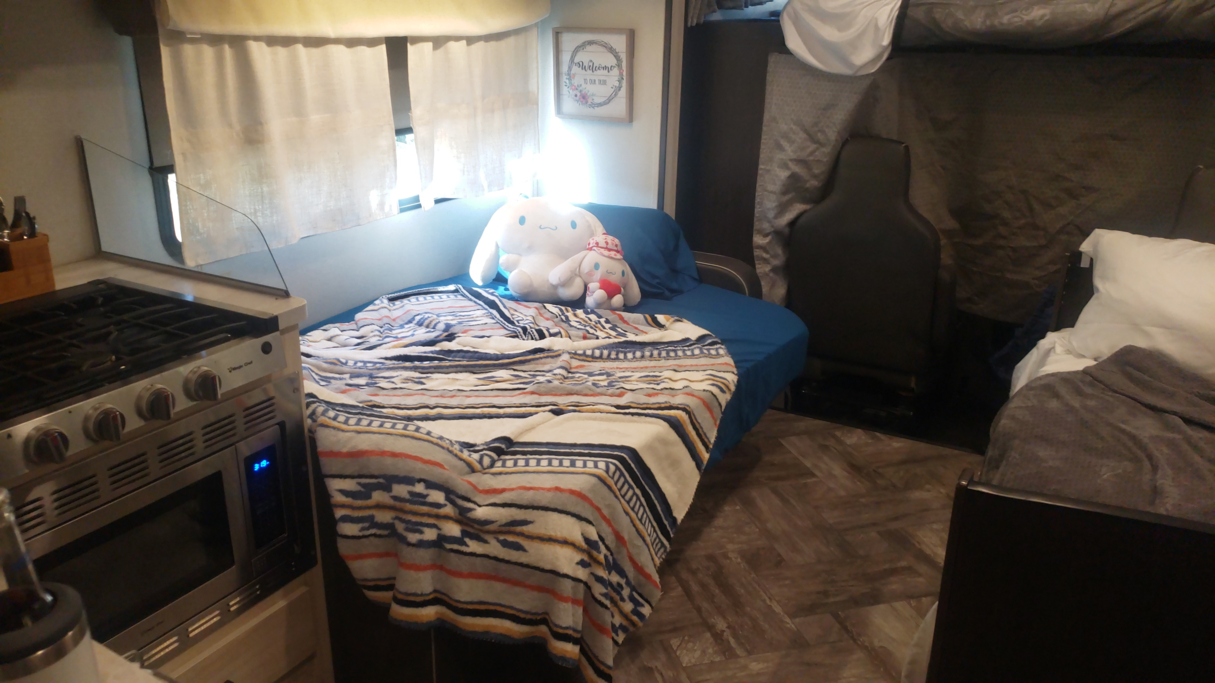 Inside this RV rental: compact kitchen with stove/microwave, a cozy bed with Cinnamoroll plushies & patterned blanket.. Forest River Sunseeker LE 2022