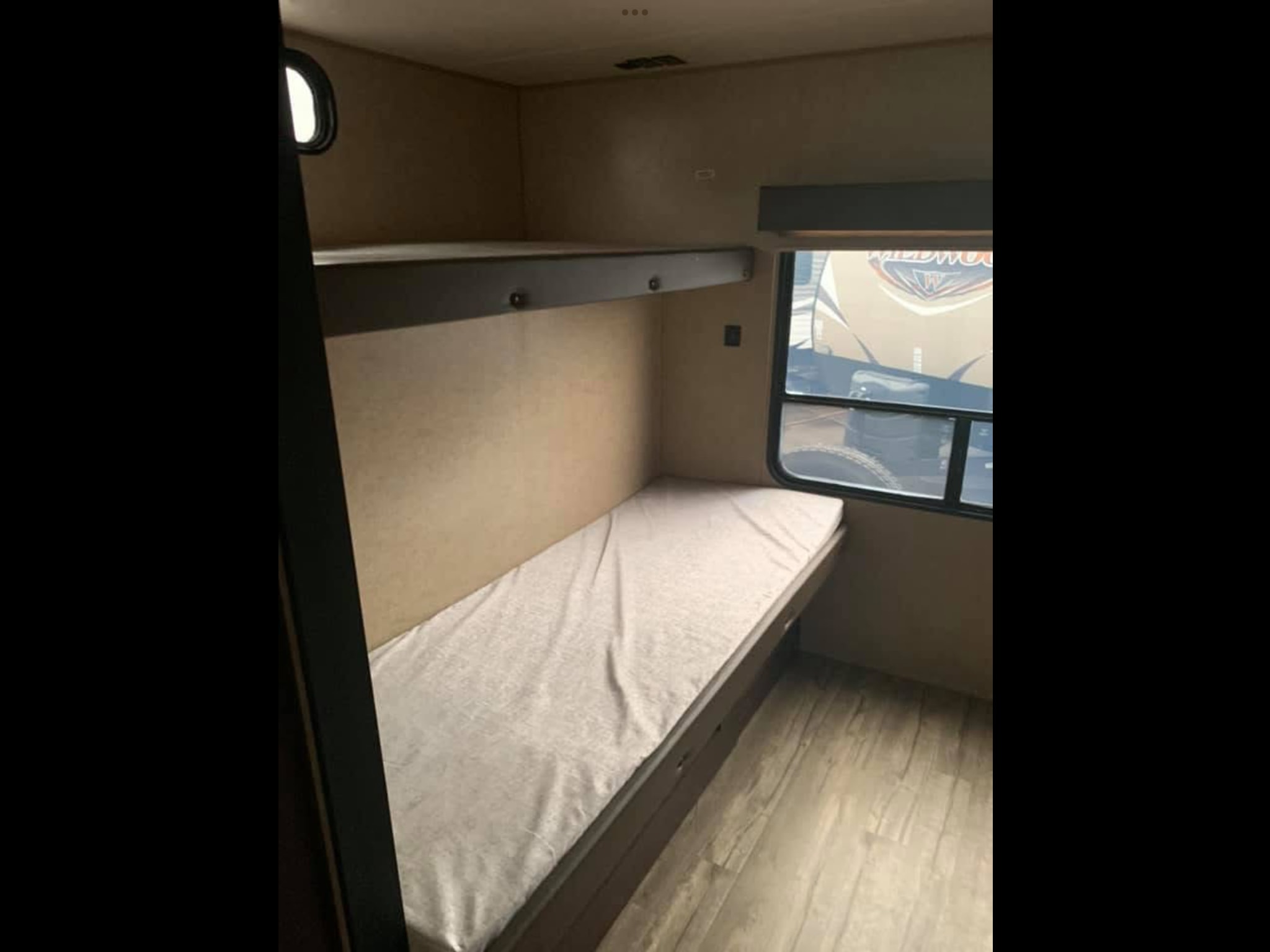 RV rental bunk beds: a lower bed with mattress, an upper bunk, a window, and wood-look flooring. Perfect for camping trips.. Forest River Cherokee 2018