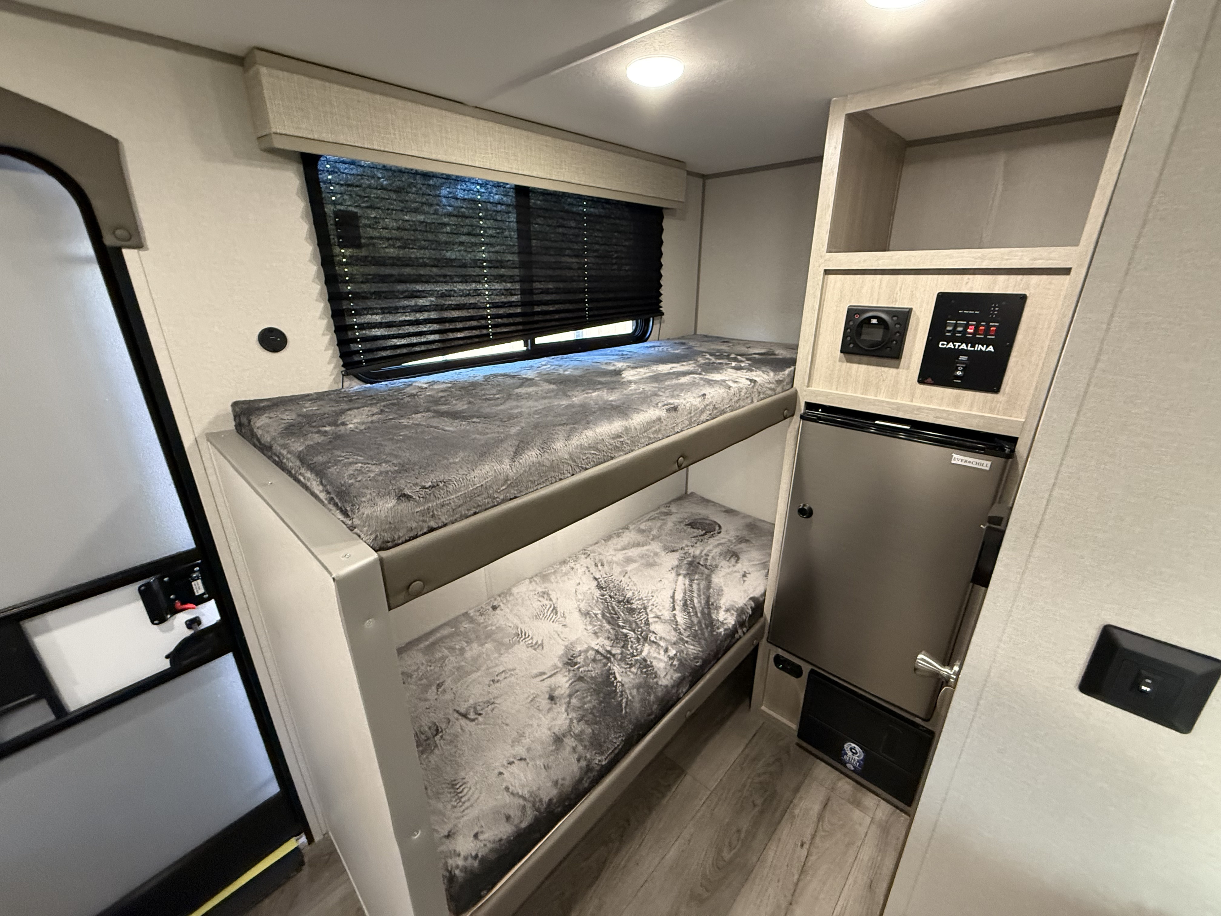 RV rental bunk room: features two cozy bunks with patterned mattresses, a window, compact fridge, and system controls.. Coachmen catalina 2025