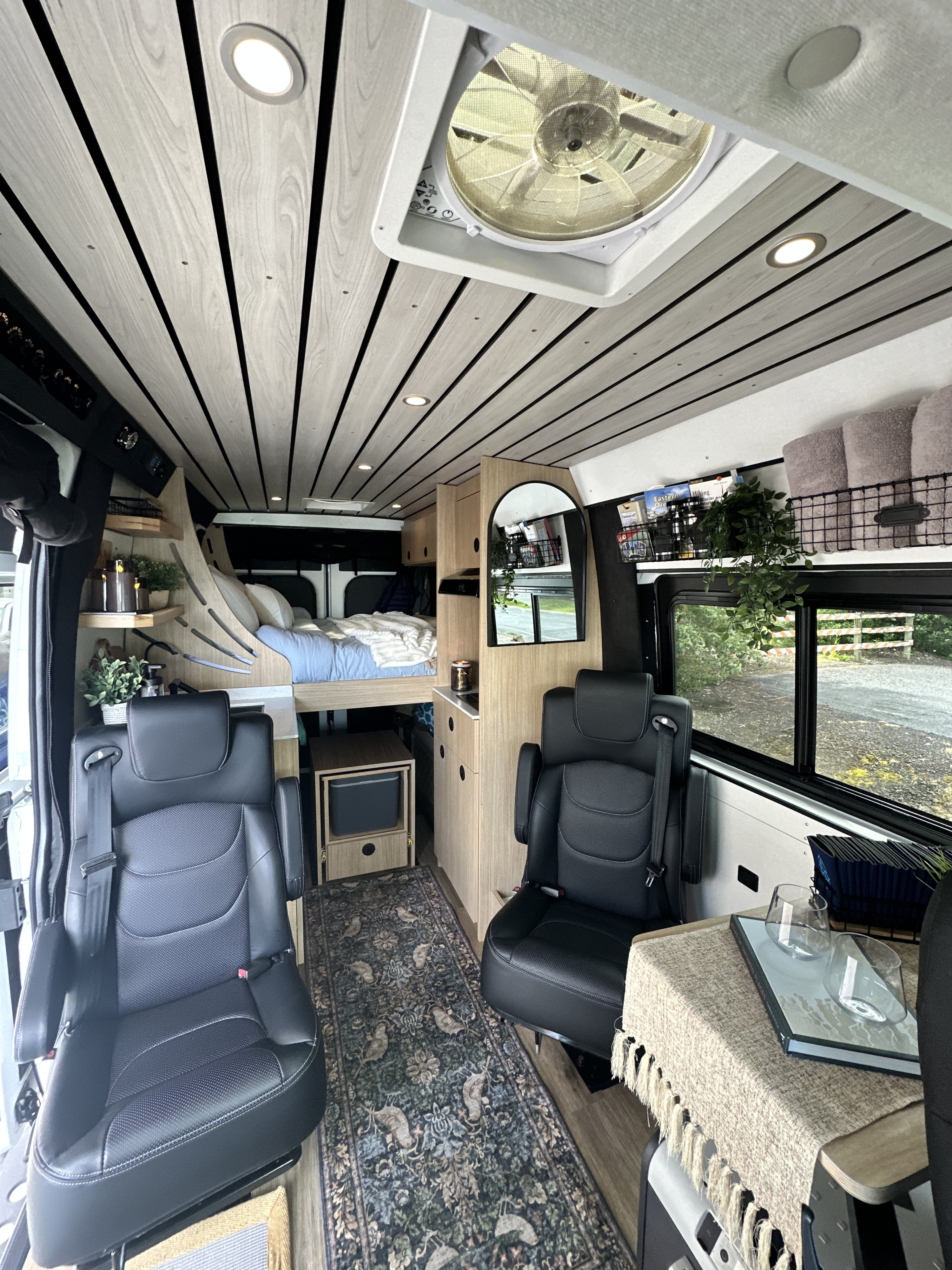 Step into this modern **rv rental**! The cozy campervan interior features a wood-slat ceiling, raised bed, kitchen unit, and swivel seats.. RAM RAM ProMaster 2500 2022