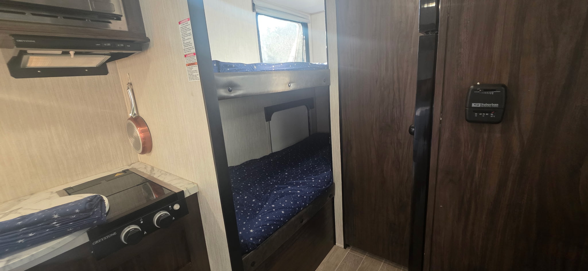 RV rental interior: bunk beds, kitchenette with Greystone stovetop, and Suburban thermostat. Compact living space details.. Forest River Cherokee Wolf Pup 2019