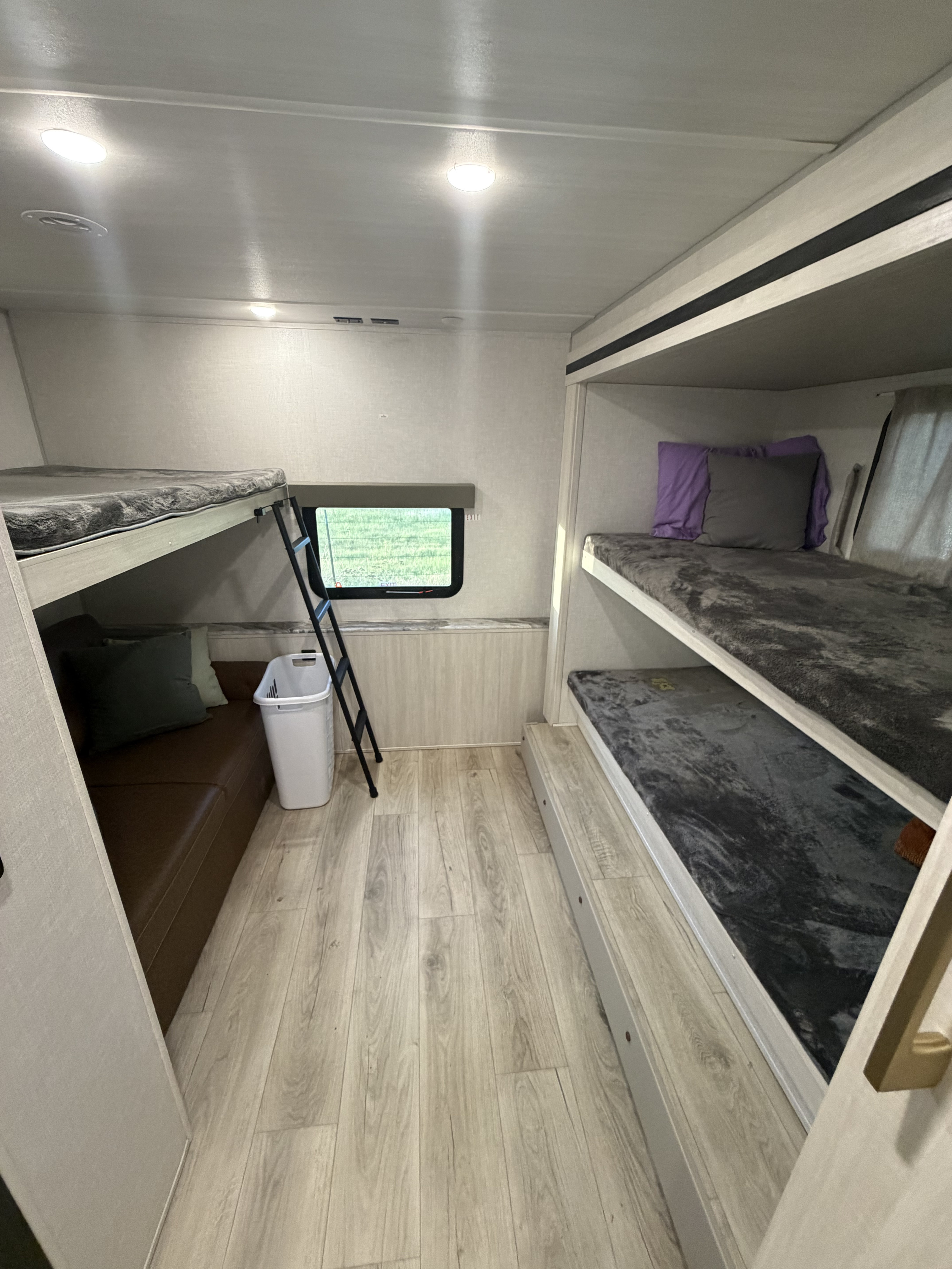 RV rental bunkroom: Light-filled interior with multiple bunk beds, cozy seating, wood-look floor, and a window.. Forest River Surveyor Legend 2024