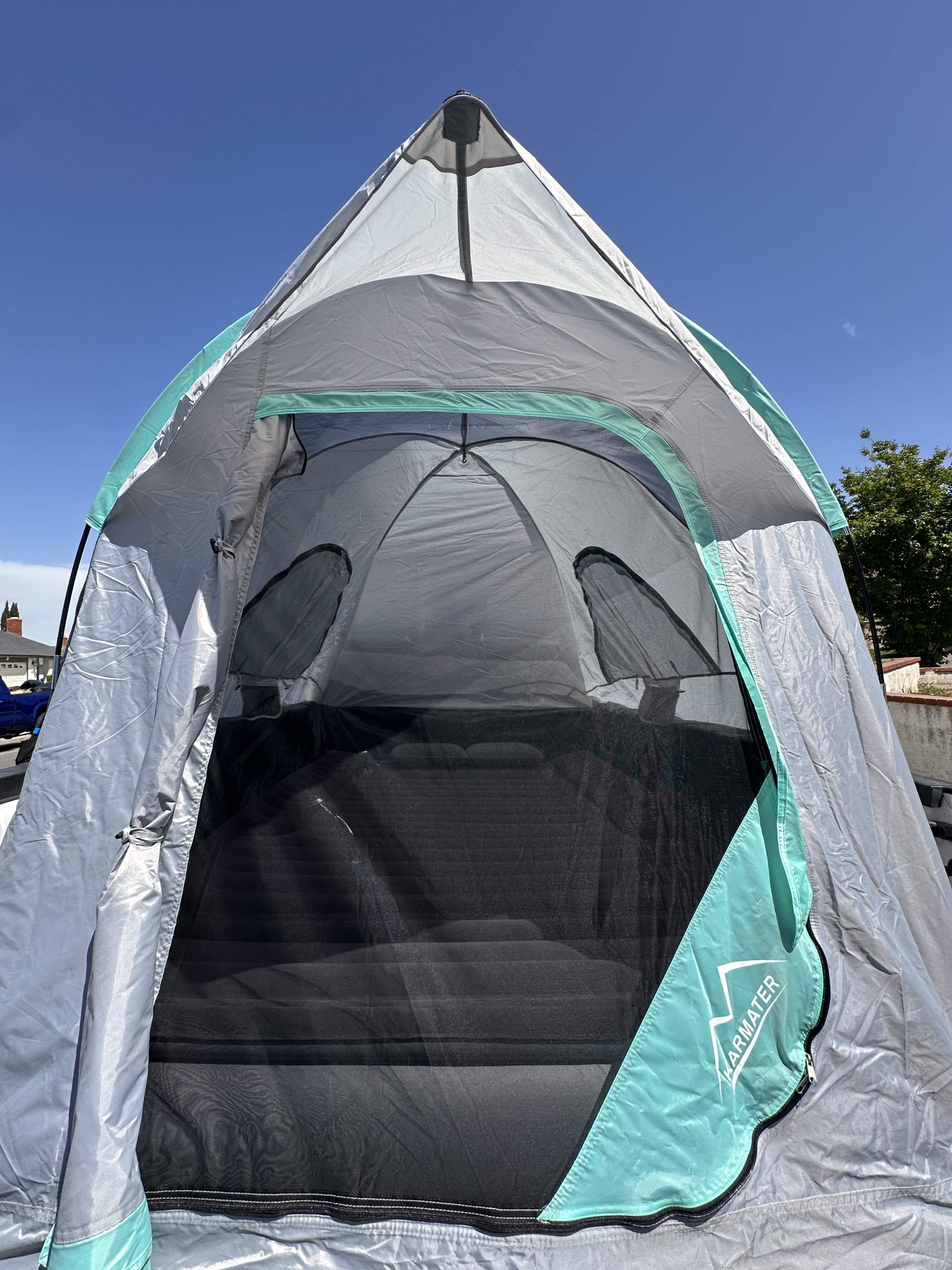 This grey and teal pop-up tent with an air mattress offers comfy outdoor sleeping for your next rv rental adventure under a blue sky.. Ford F-150 2011
