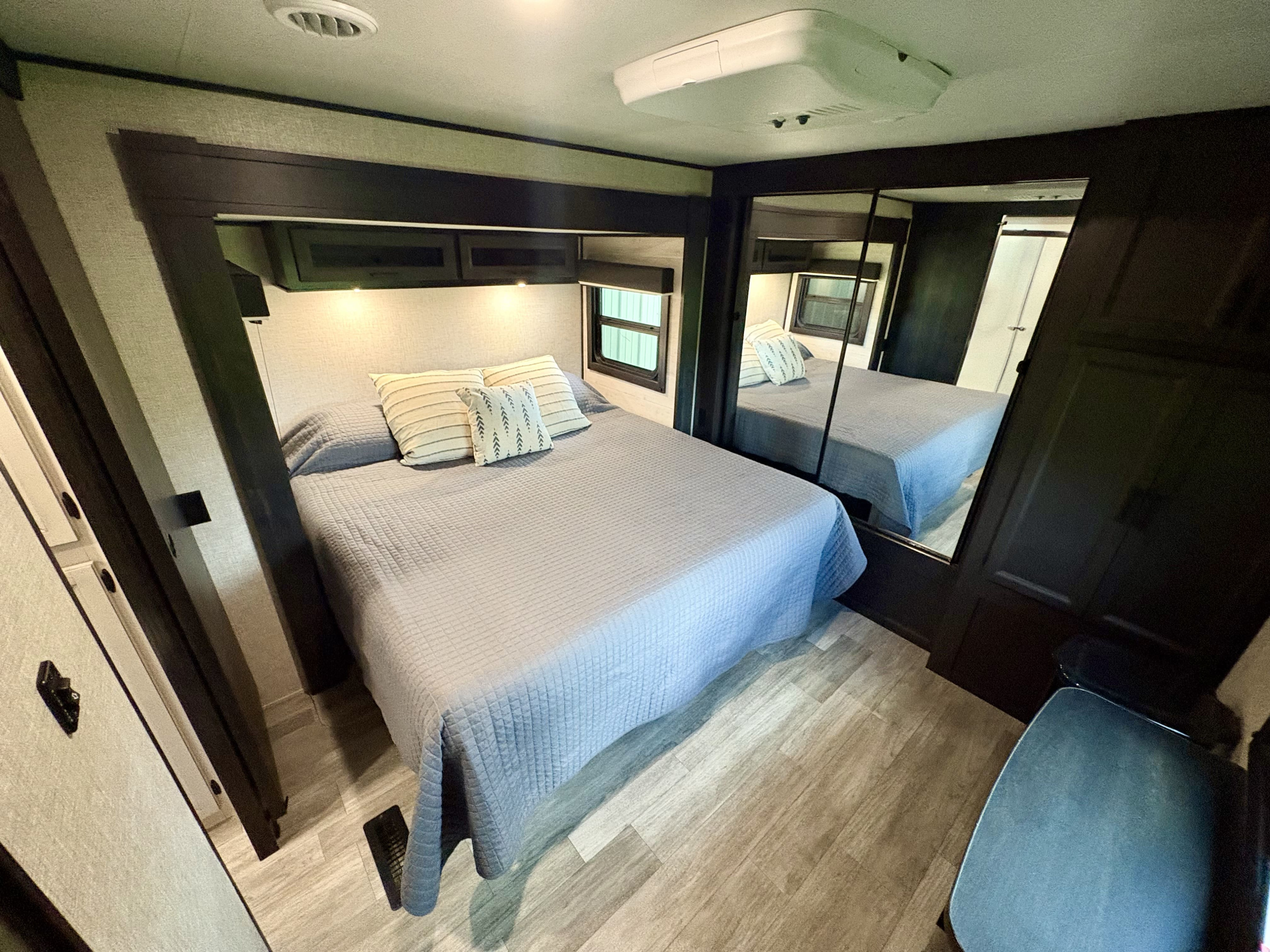 Spacious RV rental bedroom with queen bed, overhead storage, mirrored closet, and light wood flooring.. Jayco Jay Flight 2022