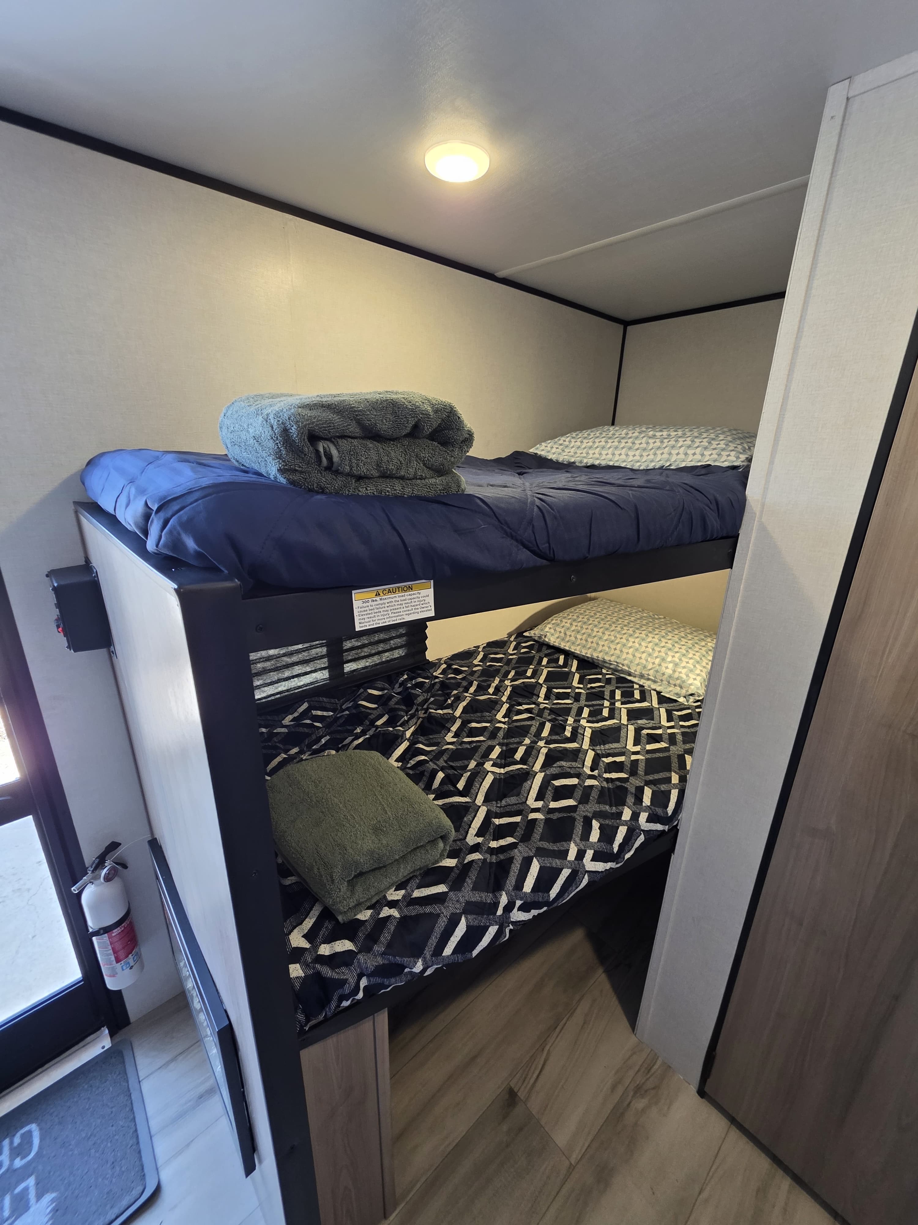An RV rental's cozy bunk beds, complete with fresh bedding, pillows, and folded towels on both top and bottom bunks.. Keystone RV Coleman 13B 2026