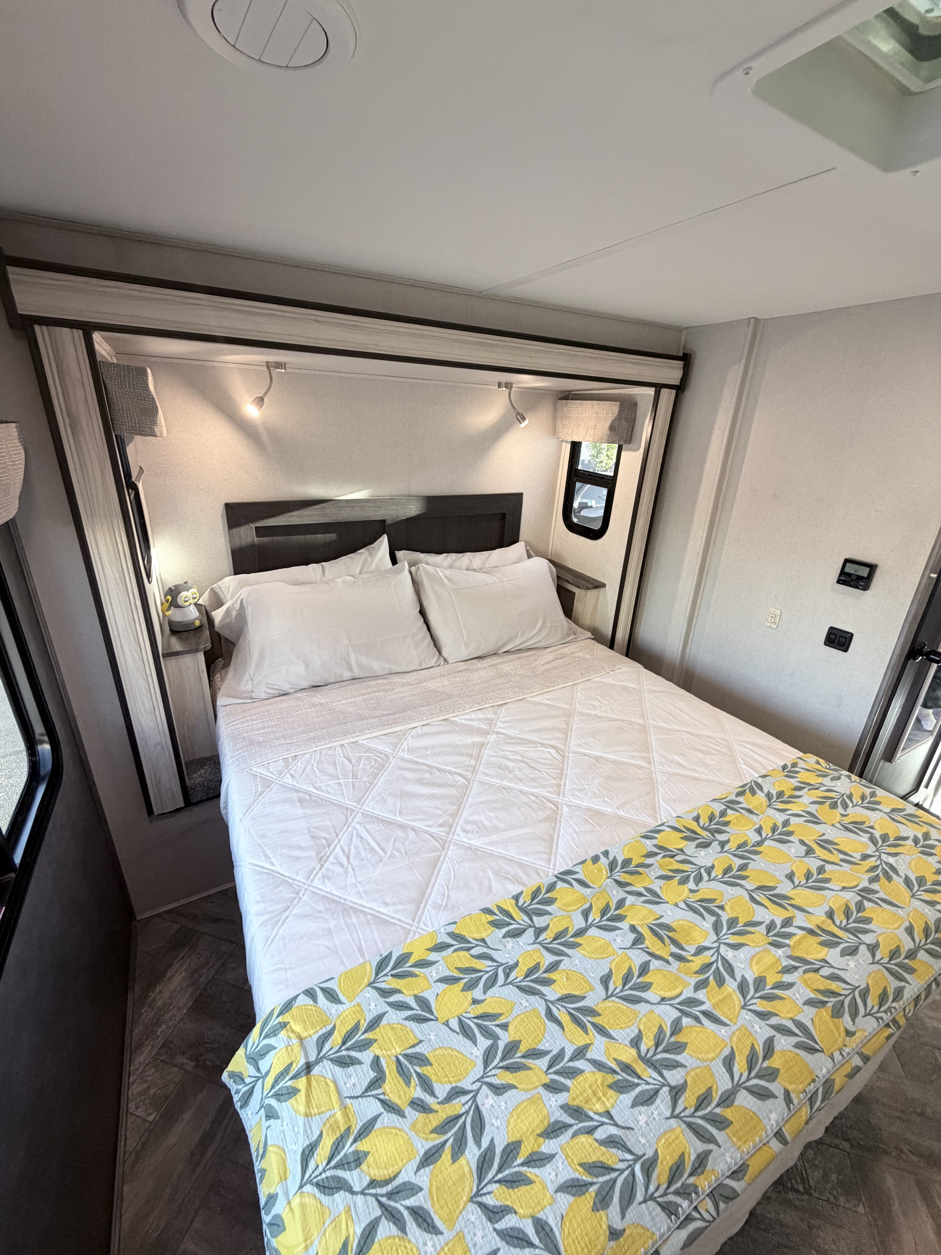 Cozy RV rental bedroom: bed with white sheets, bright lemon blanket, headboard, reading lights, and window for a comfortable stay.. Forest River Sunseeker Classic 2023