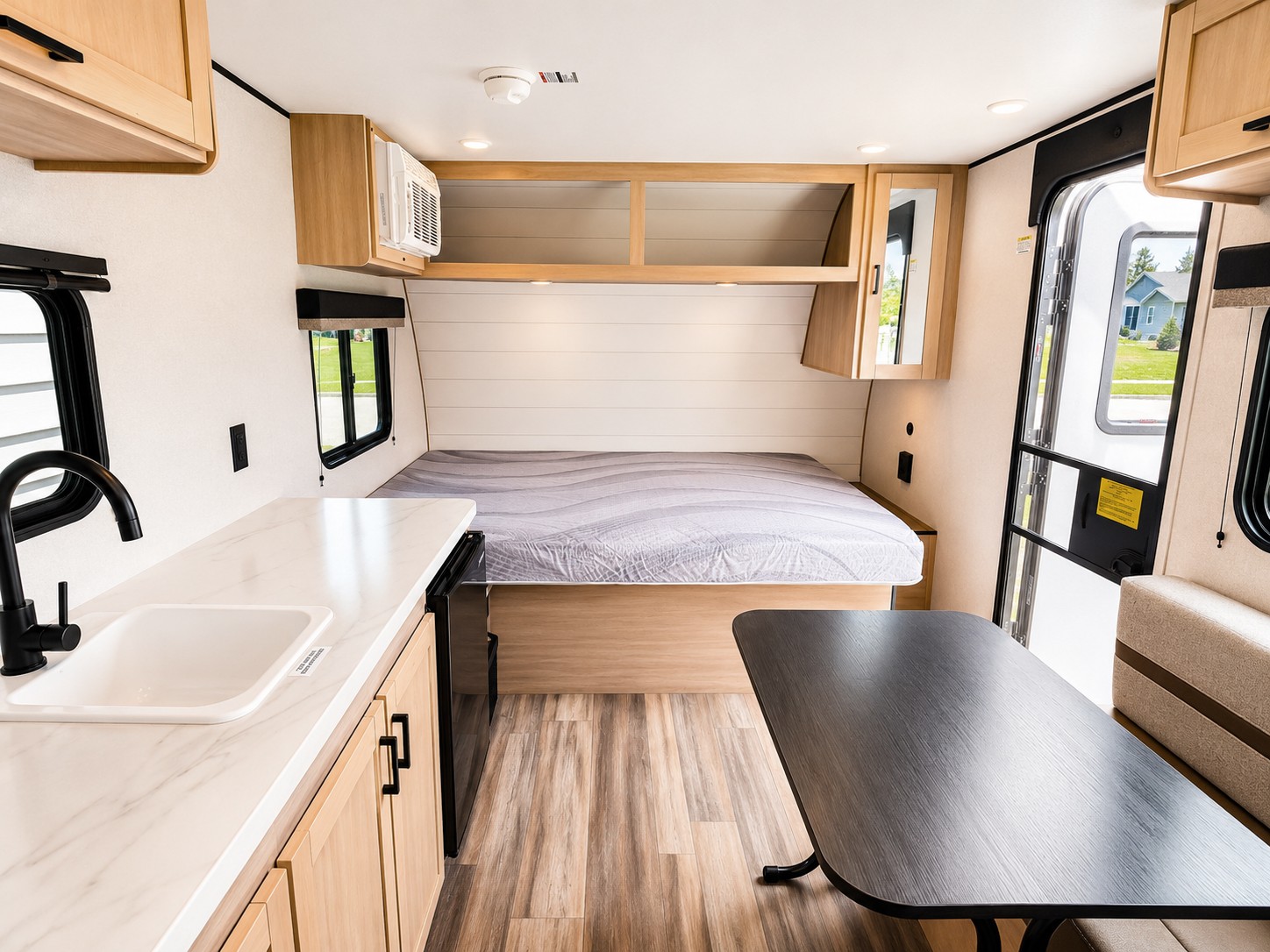 This modern RV rental interior features a kitchen with a sink, a comfortable bed, and a dining area, ideal for travel.. Highland Ridge RV Colt CTR 2026
