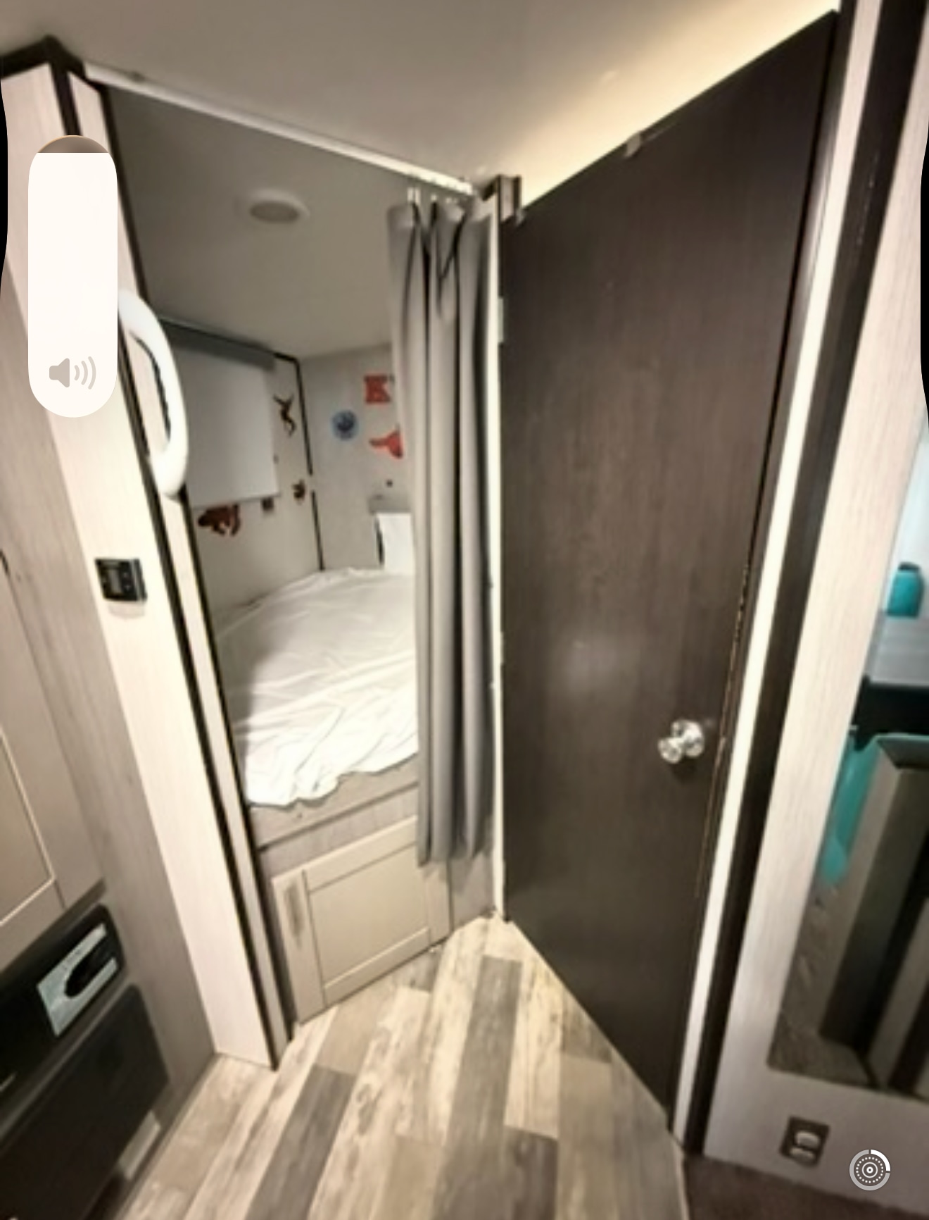 Cozy RV rental travel trailer bunk with privacy curtain, white bed, and wood floor.. Heartland RVs Mallard 2020