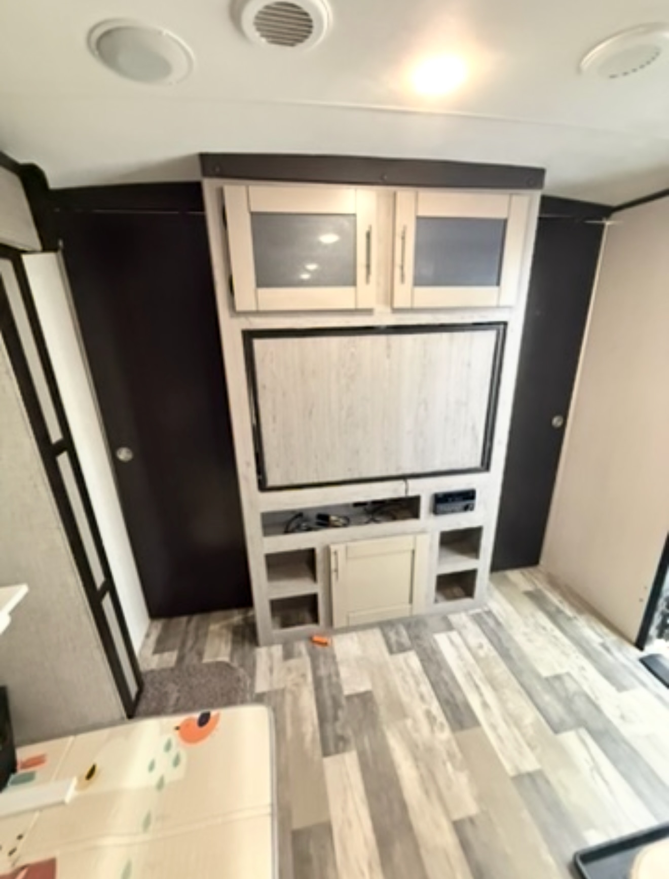 Cozy rv rental interior featuring a modern entertainment center with a TV, ample storage, and light wood-look flooring.. Heartland RVs Mallard 2020