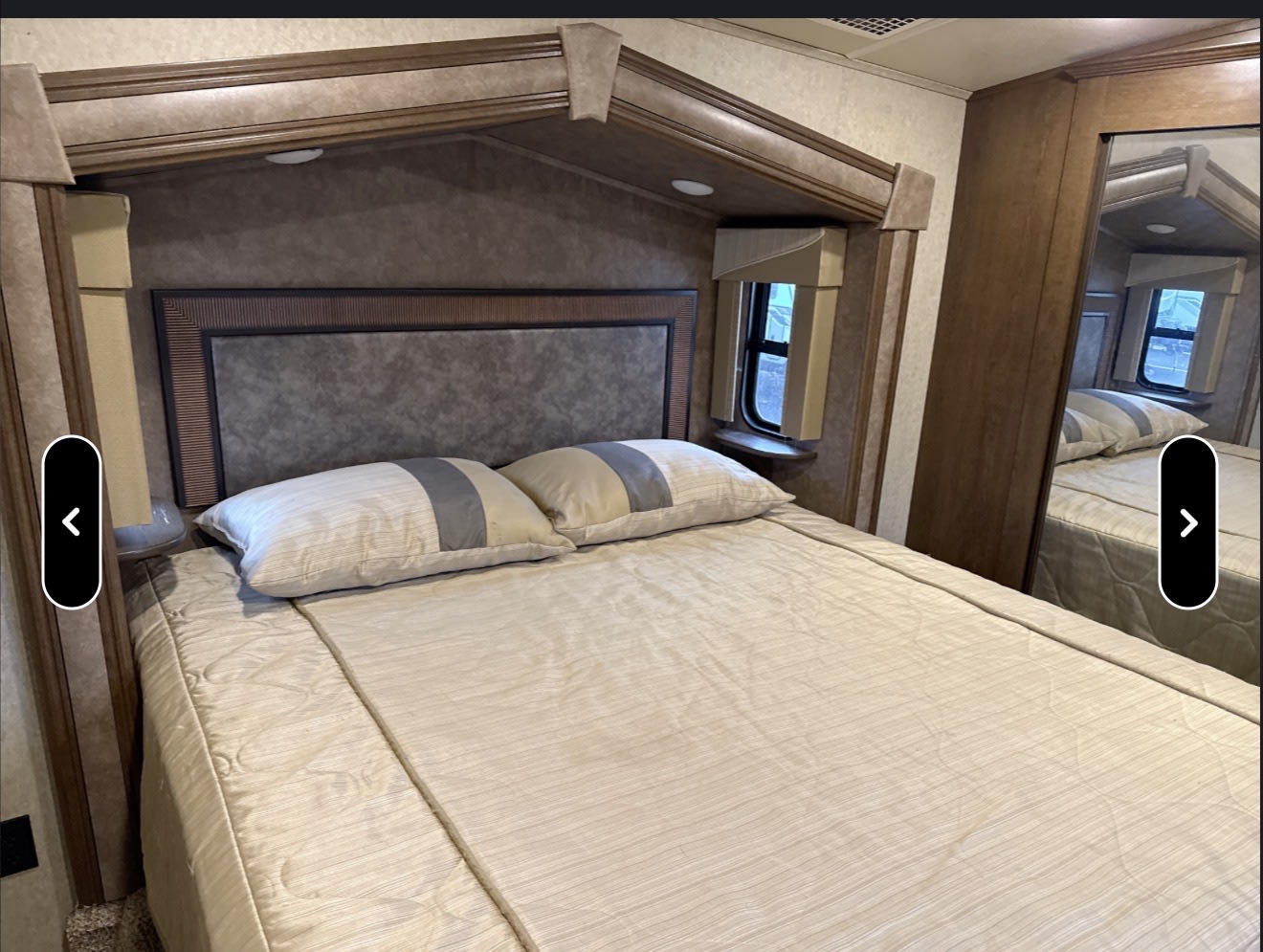 Cozy rv rental bedroom features a comfortable bed, padded headboard, window, and mirrored closet, ready for your travels.. Forest River Cedar Creek Silverback Edition 2017