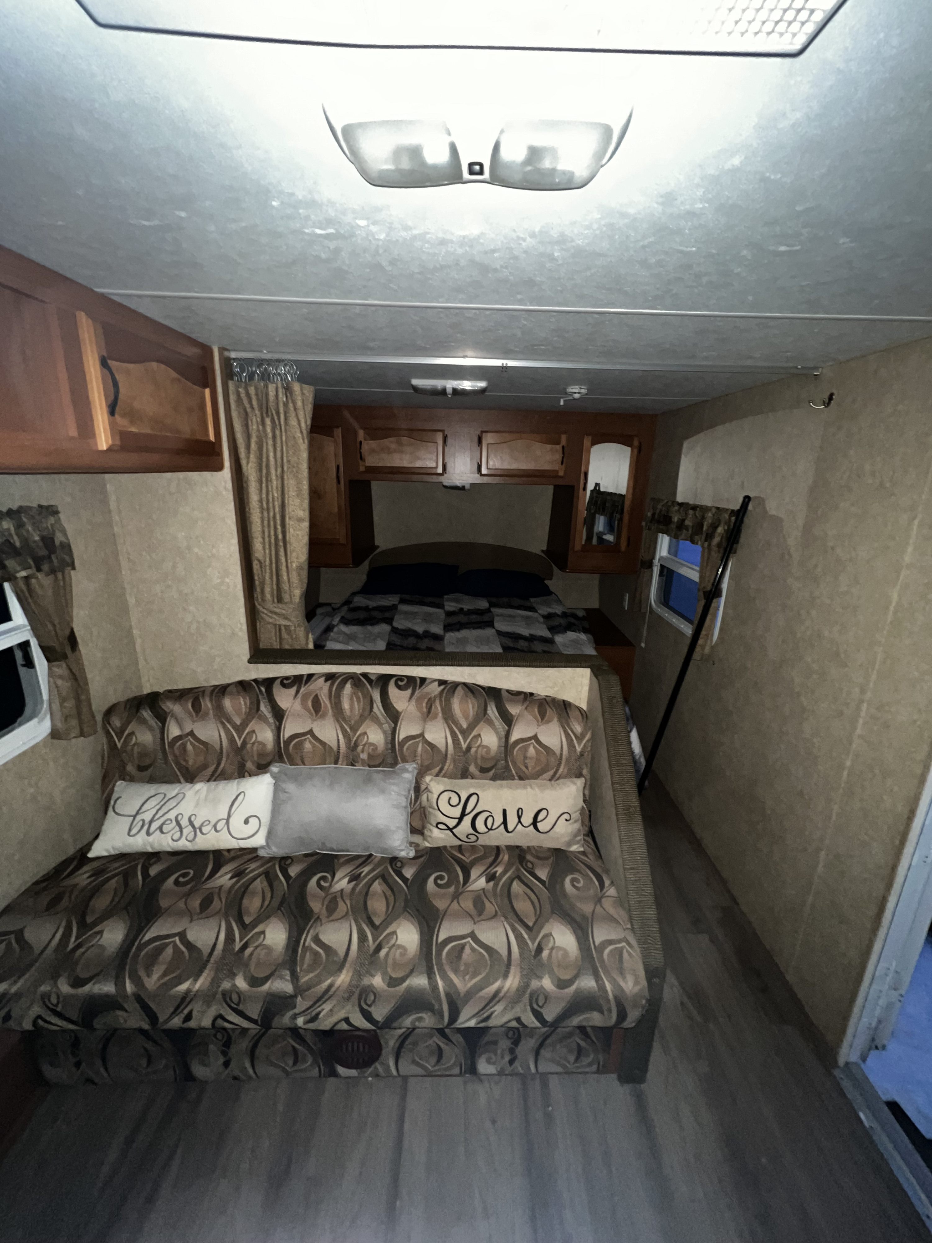 Cozy rv rental interior: A patterned sofa with "Blessed" & "Love" pillows, plus a comfortable bedroom.. Forest River Wildwood 2011
