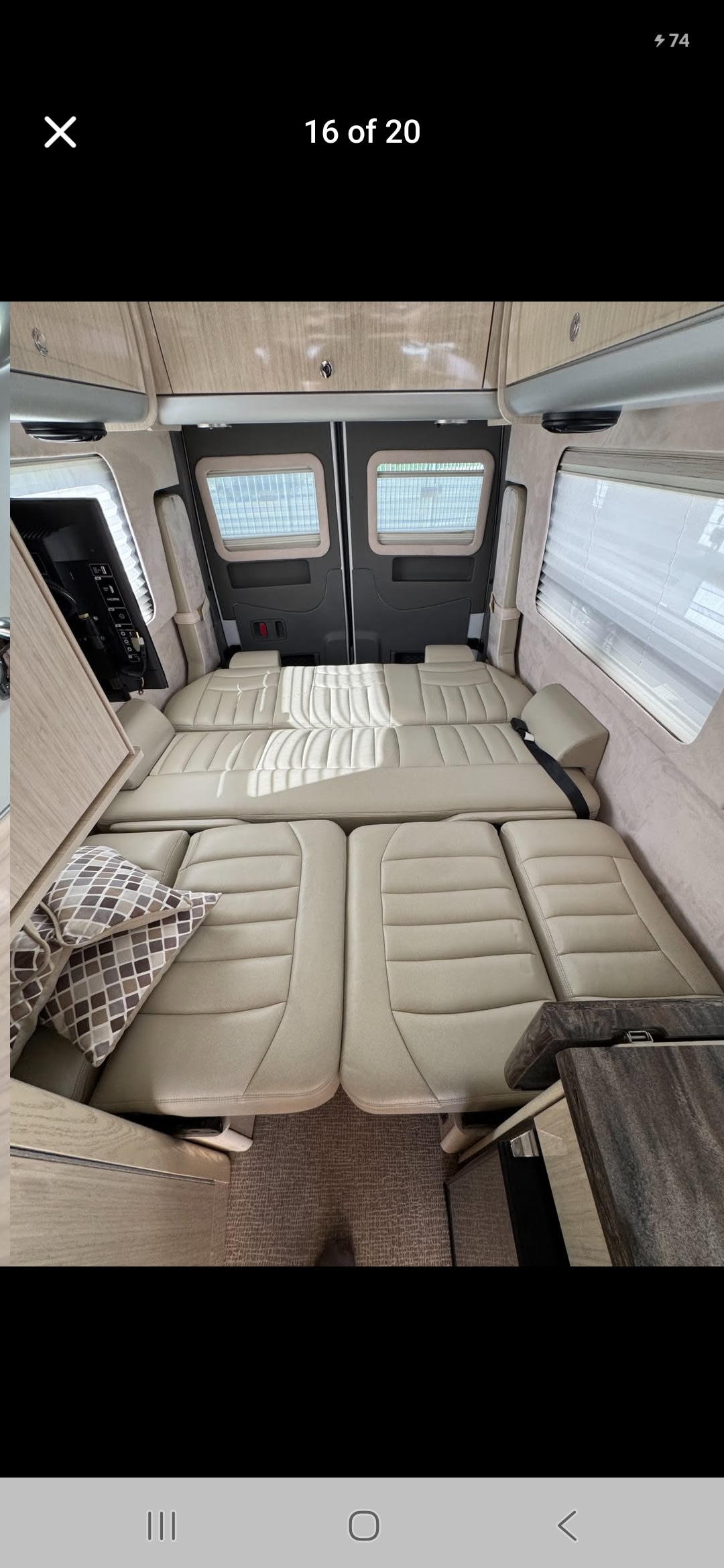RV rental interior with versatile modular seating that converts into a bed, featuring light-colored cushions, windows, and overhead storage.. Airstream Interstate 2013