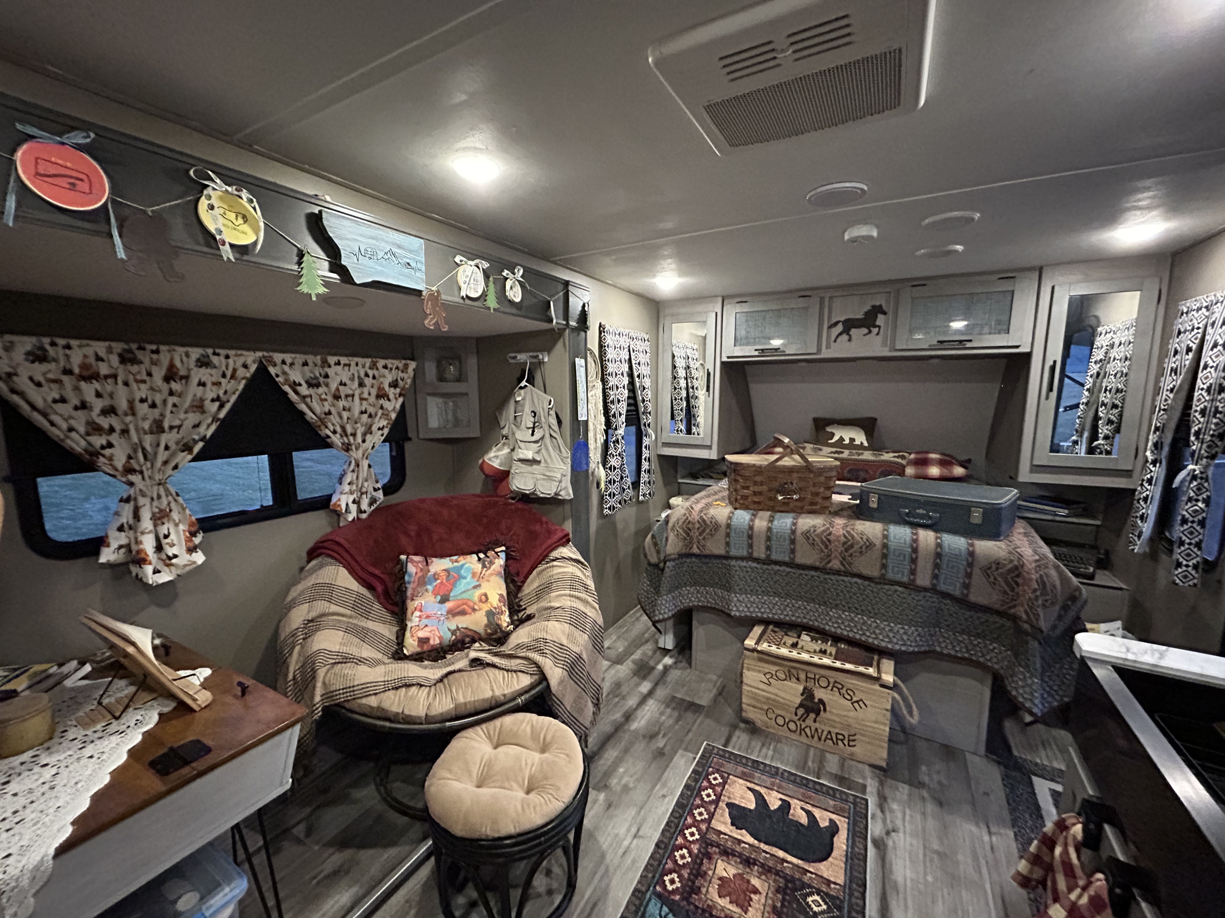 Cozy RV rental interior with a comfy bed, papasan chair, and charming camping-themed decor, ready for your next adventure.. Dutchmen Coleman Light 2023