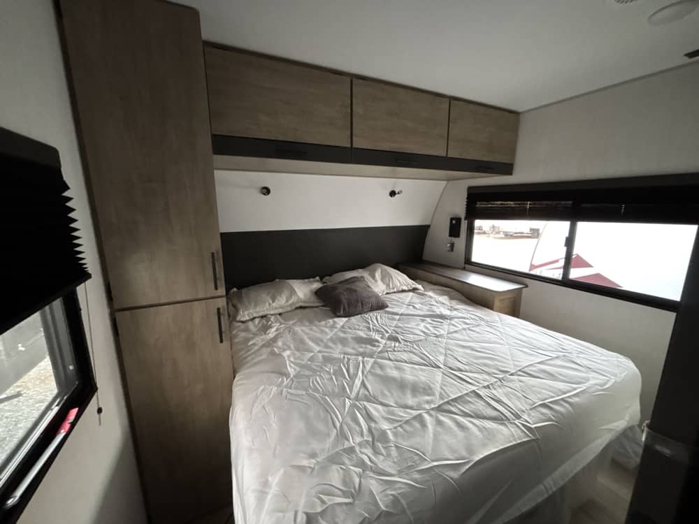 RV rental's inviting bedroom: comfortable bed, built-in storage, and windows with blinds for a cozy stay.. Forest River Campsite Reserve 2026