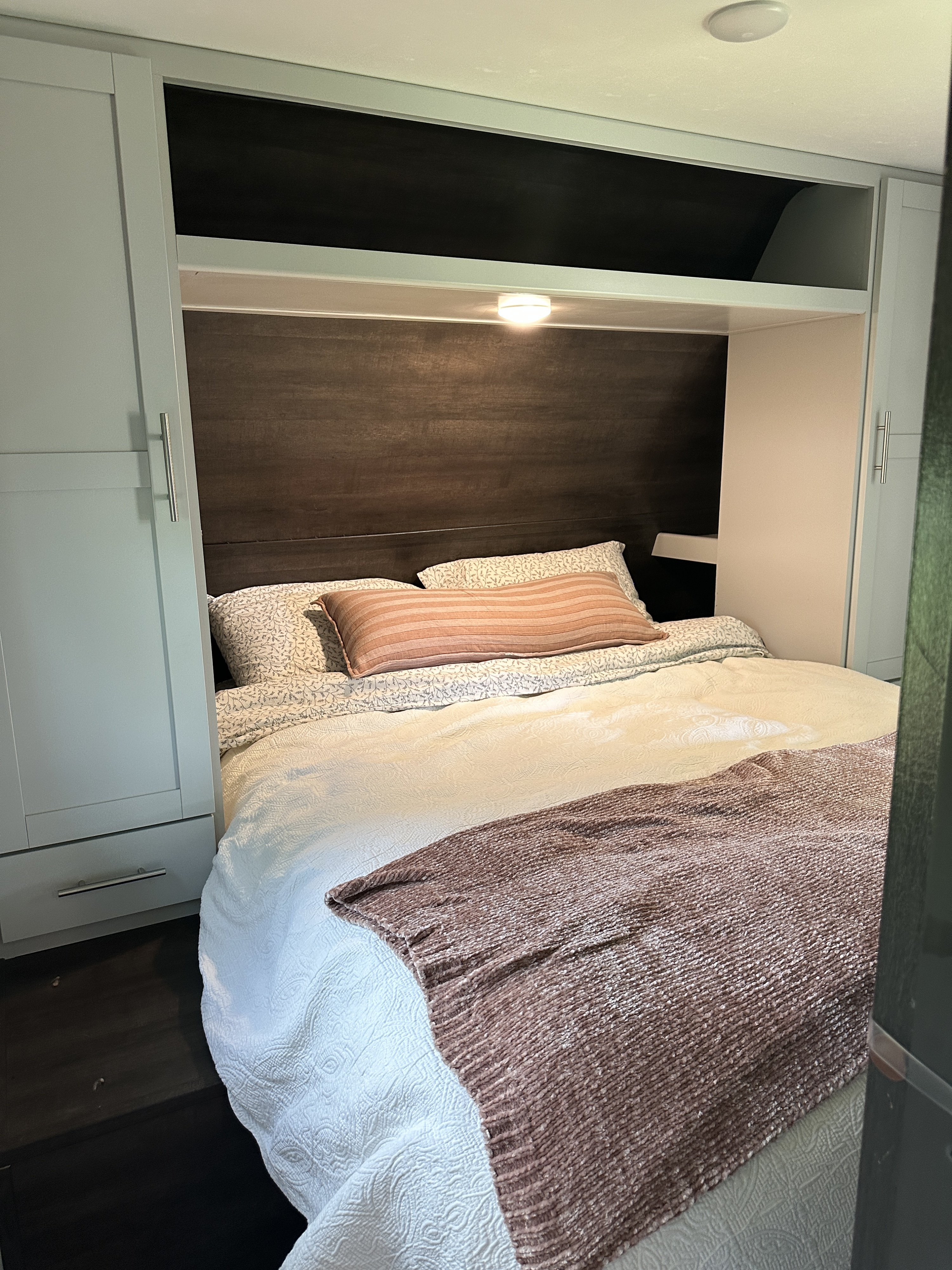 RV rental's compact and inviting bedroom, featuring a comfortable bed, built-in storage, and warm lighting.. Keystone RV Bullet Crossfire 2021