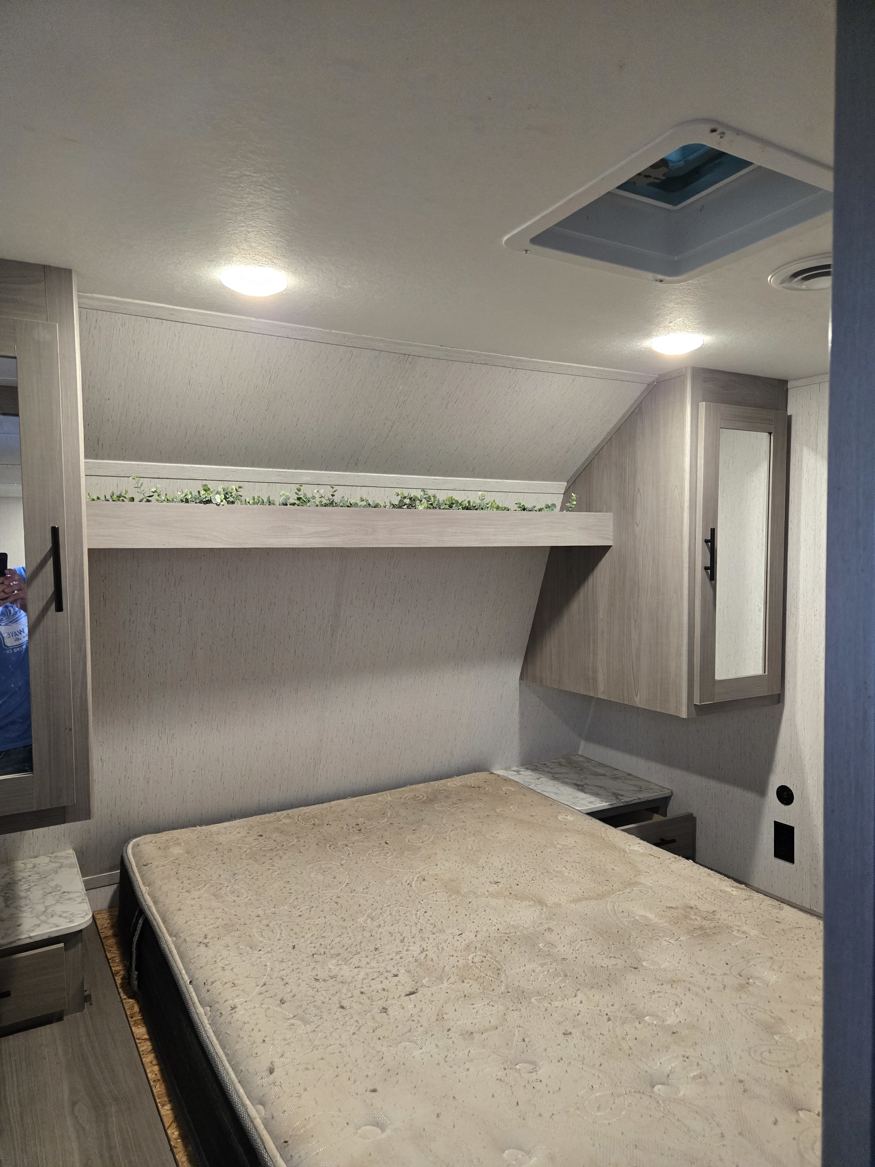 RV rental bedroom with mattress, decorative shelf, storage cabinets, ceiling lights, and vent.. Dutchmen Coleman Lantern 2021