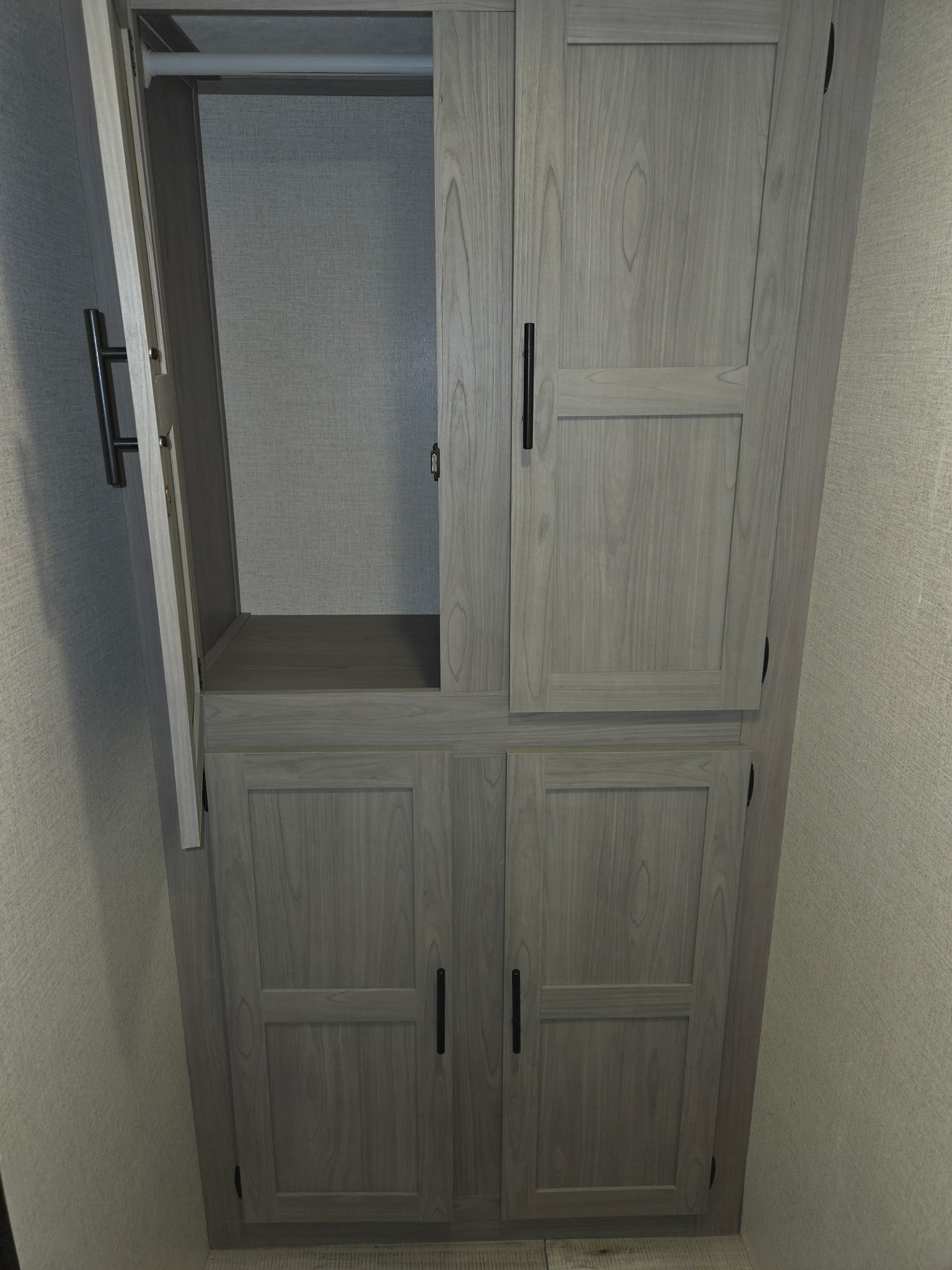 RV rental: Modern light gray wood closet with an open door showing a hanging rod and a bottom shelf for storage.. Keystone RV CM17R23 2023