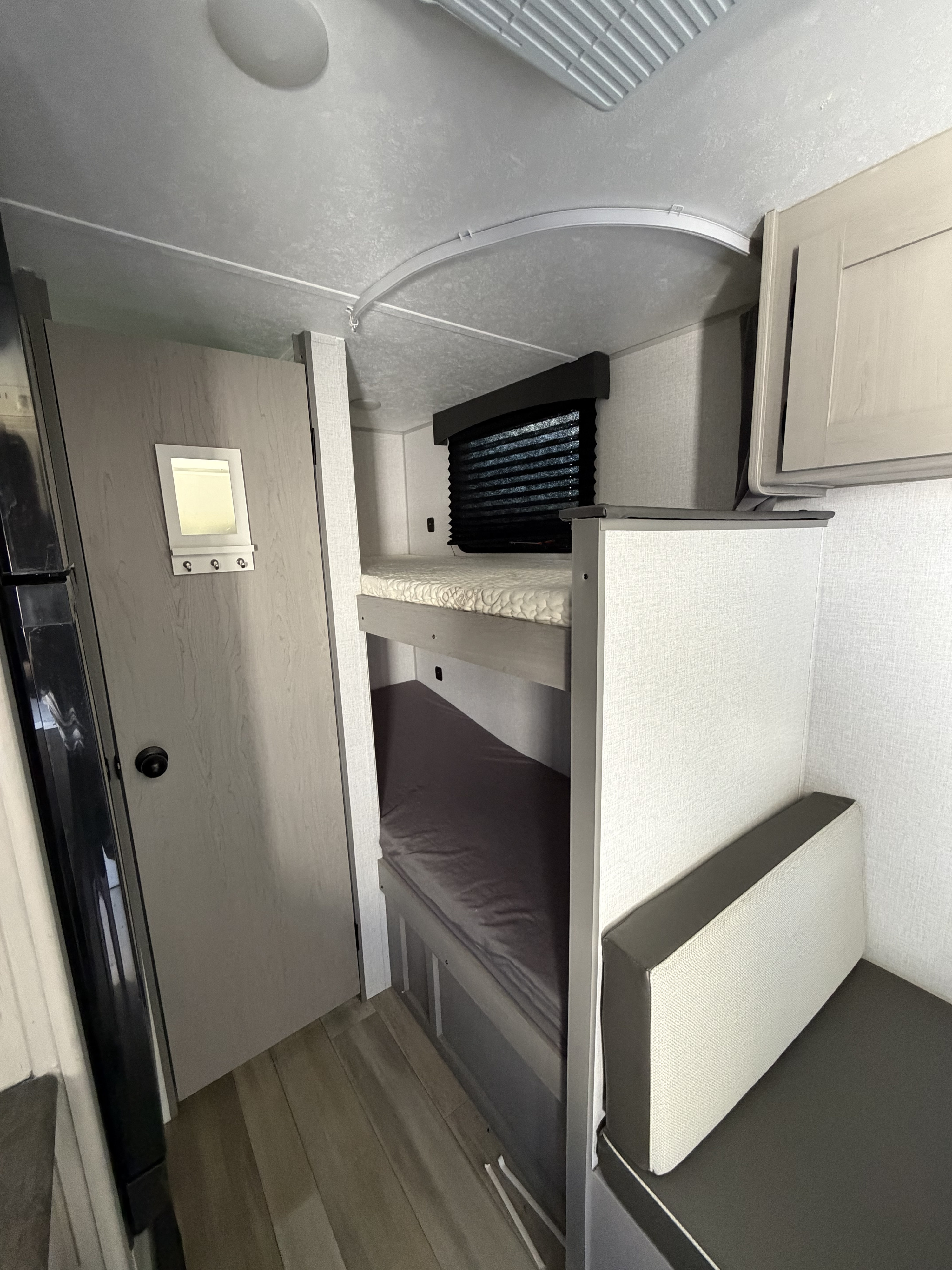 RV rental interior featuring bunk beds, a dinette seating area, and a door with a mirror. A compact, functional living space.. Coachmen Clipper 17CBH 2024