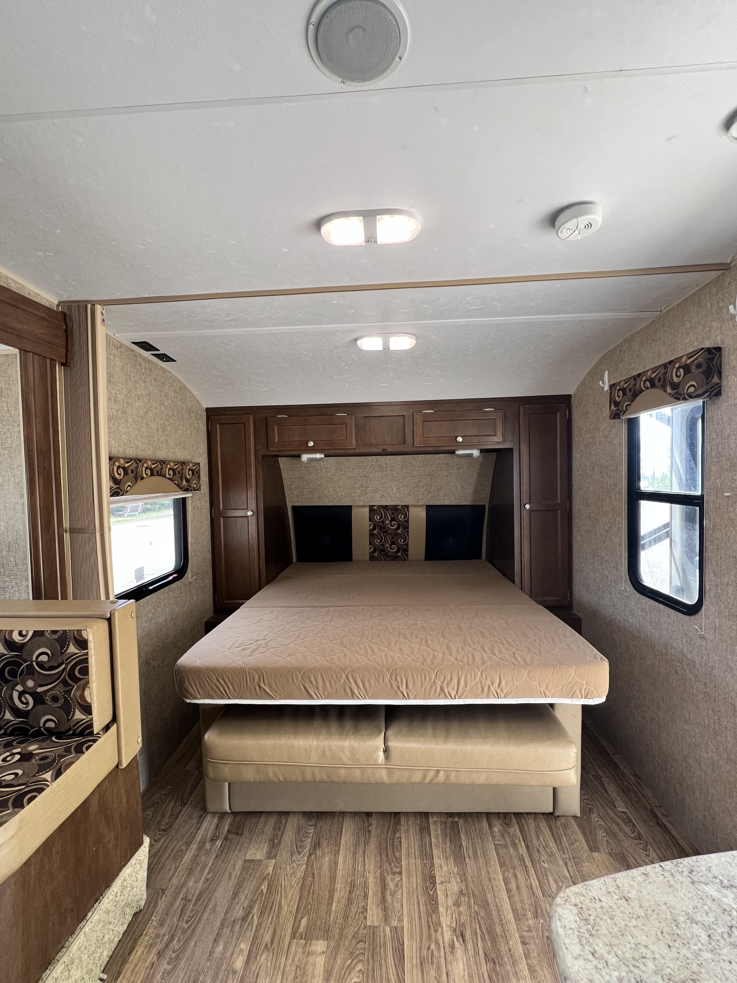 RV rental bedroom interior featuring a bed, overhead cabinets, and wood-look flooring. Perfect for a cozy getaway.. Sonic Sonic Trailer 2015