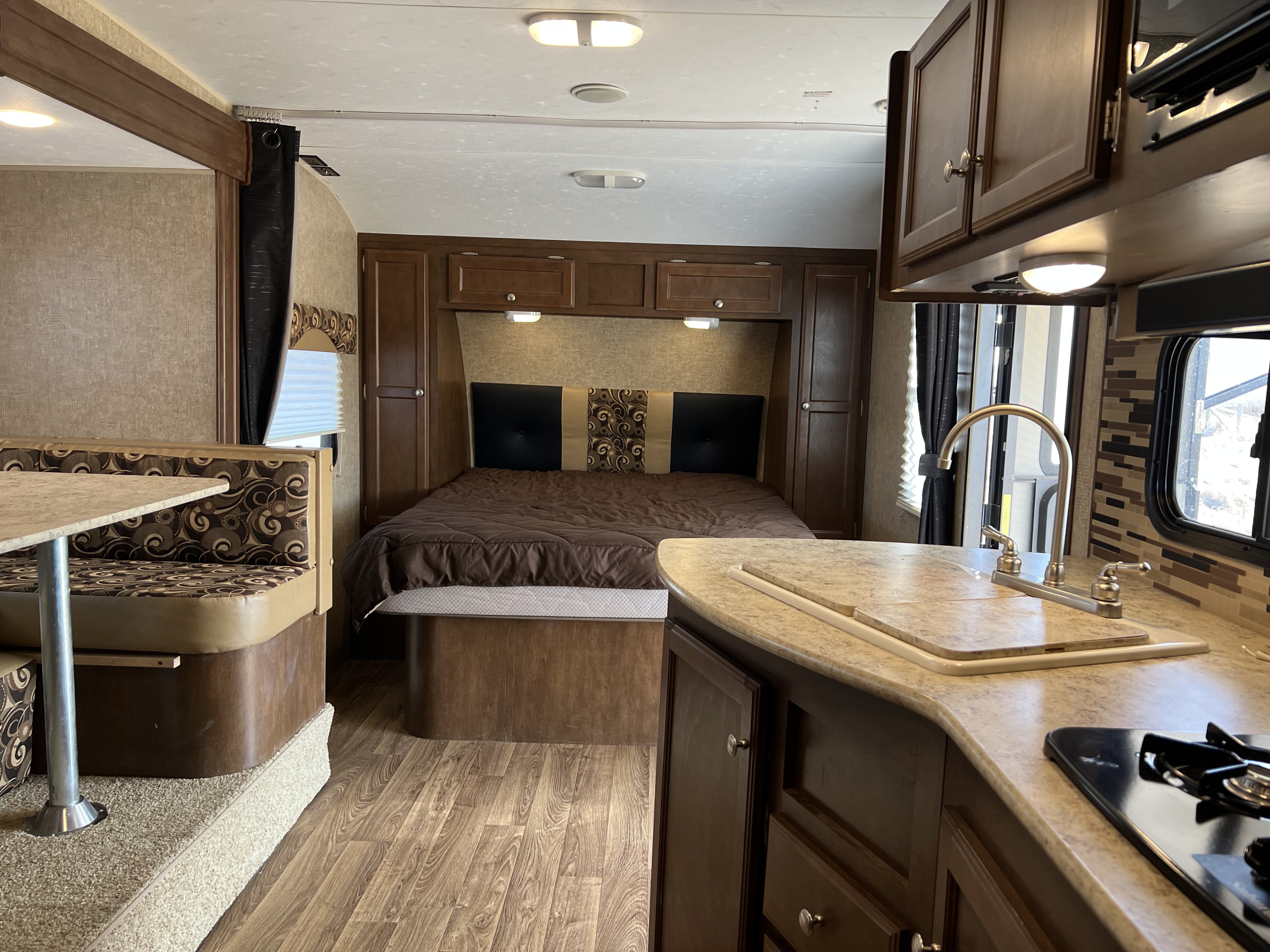 View of an RV rental's inviting interior: bed, dinette, and kitchen with counter space, sink, and stove, ready for travel.. Sonic Sonic Trailer 2015