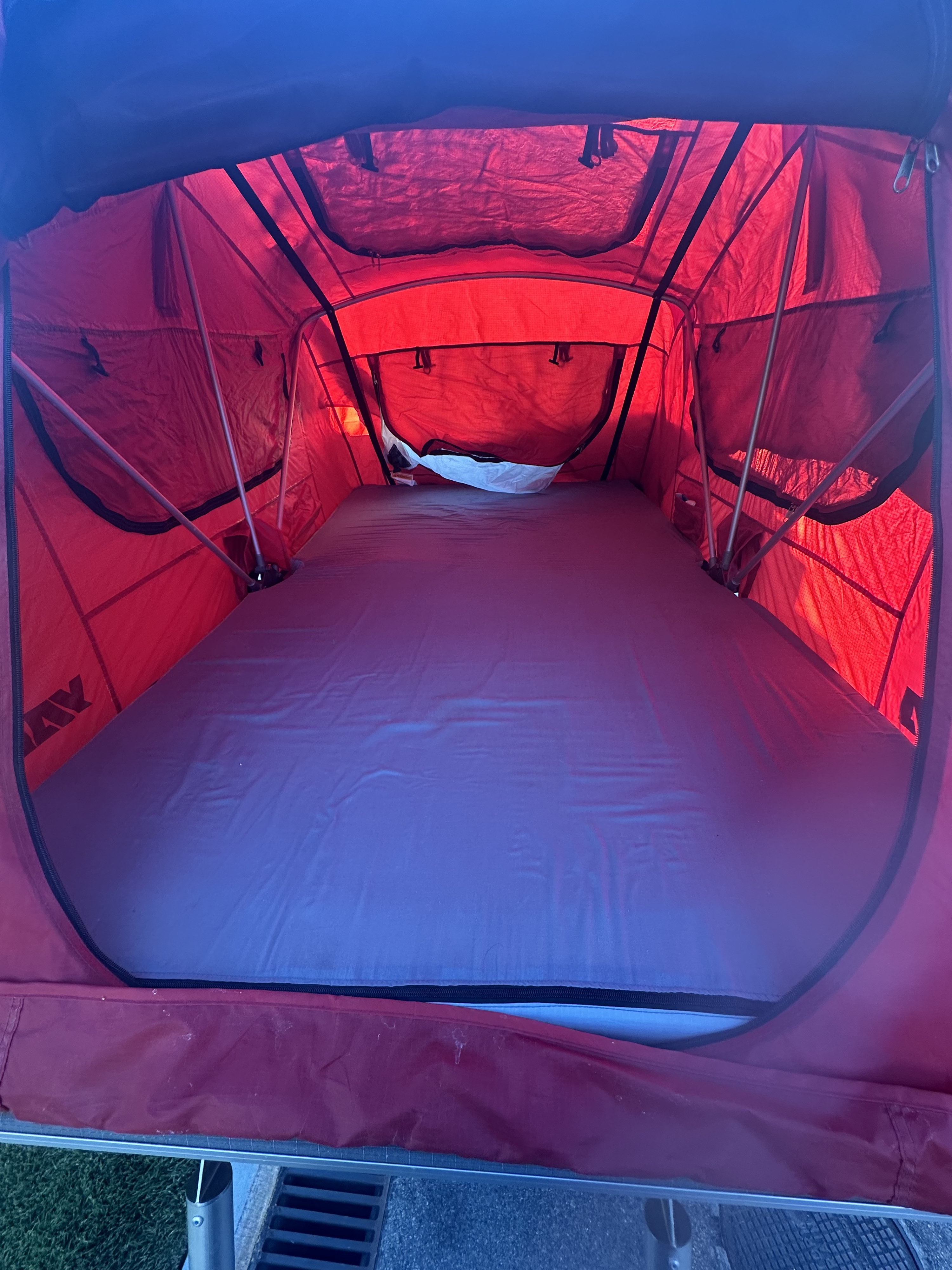Inside a red rooftop tent, ideal for RV rental, featuring a comfortable mattress for your next outdoor adventure.. Custom Built Standy Karavan 2020