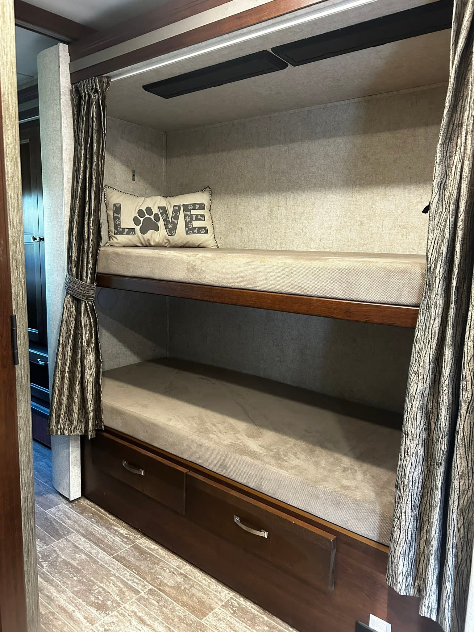 RV rental bunk beds feature light mattresses, a "LOVE" paw print pillow, privacy curtains, and storage drawers.. Forest River Ford 2019
