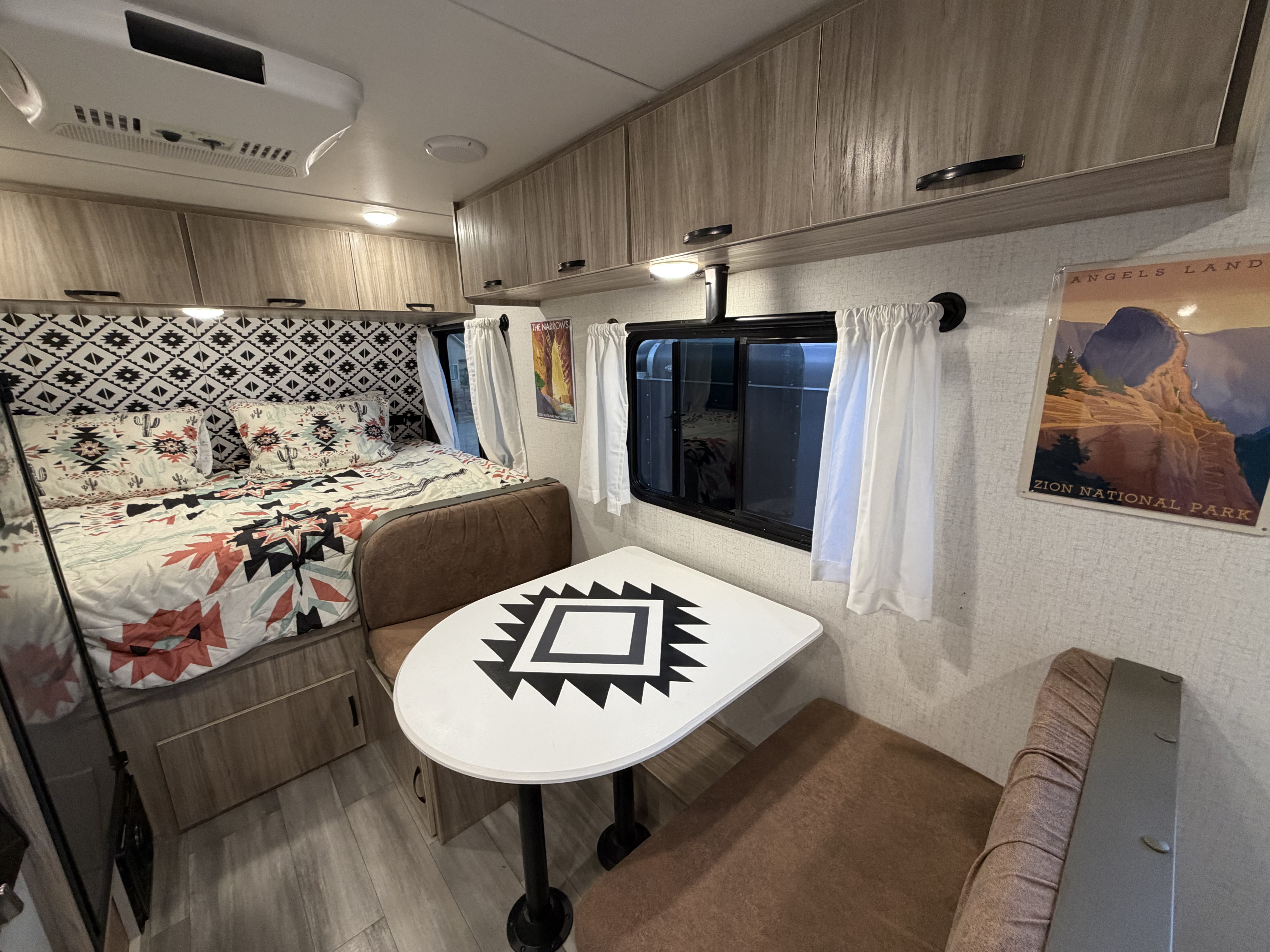 Cozy rv rental interior with Southwestern decor, a comfortable bed, and dinette for travel enthusiasts.. Minnie Micro Minnie 2022
