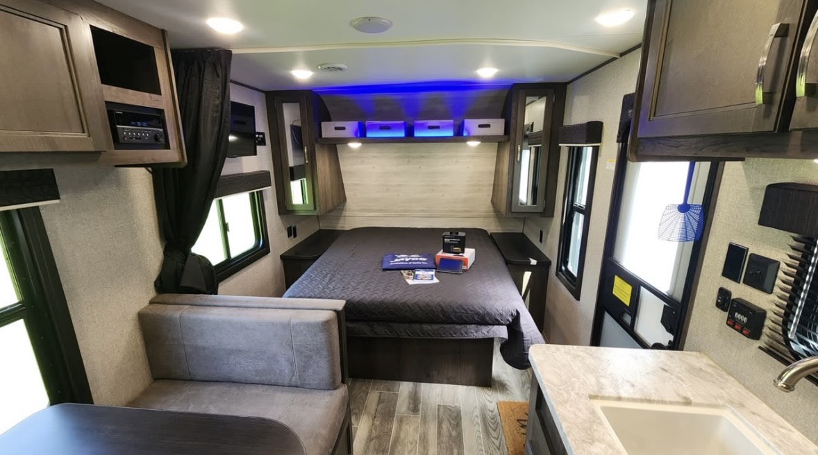rv rental interior: bed with blue accent lighting, dinette seating, and kitchen counter.. Jayco Jay Flight SLX 2021