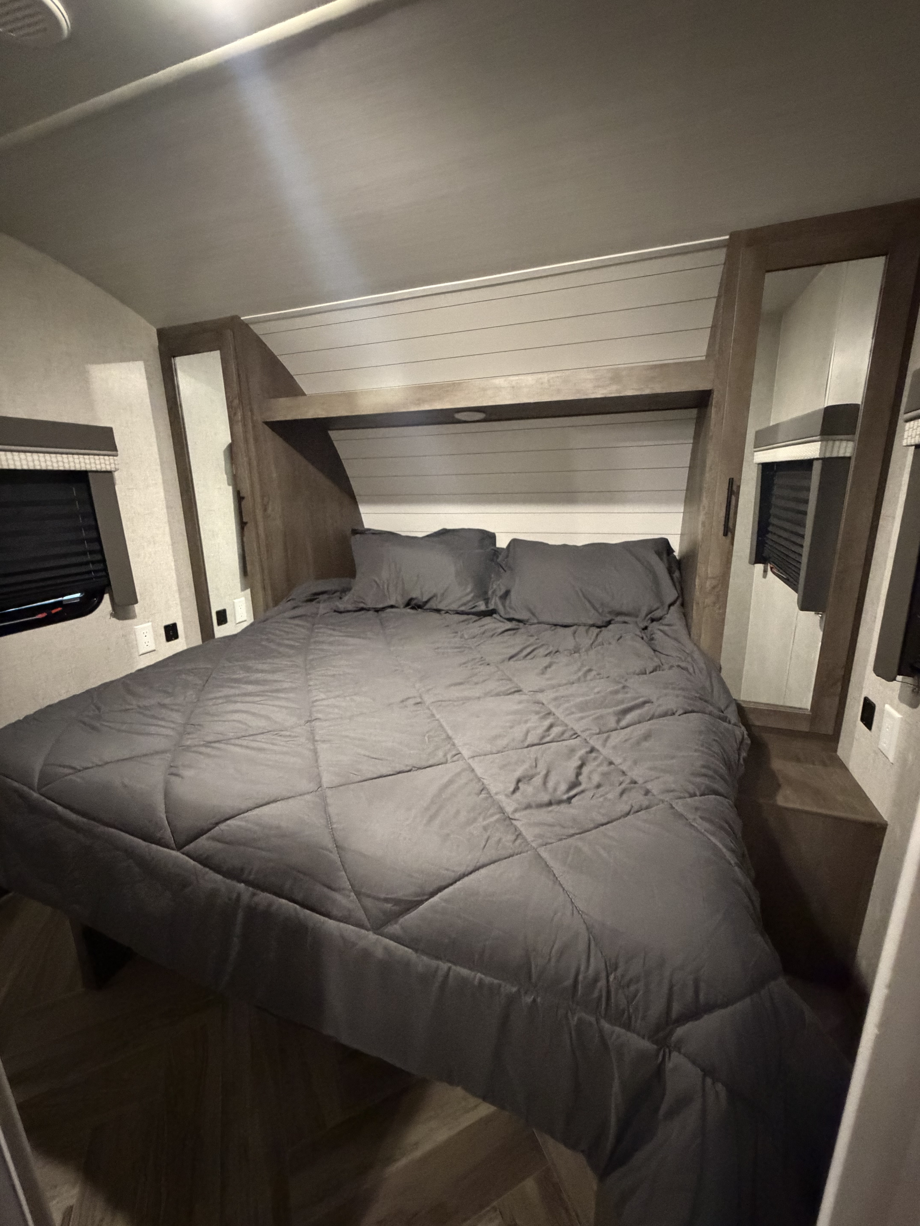 Cozy RV rental bedroom featuring a comfy bed with gray linens, mirrored closets, and overhead shelf lighting. Relax in style!. Forest River Salem Cruise Lite 2021