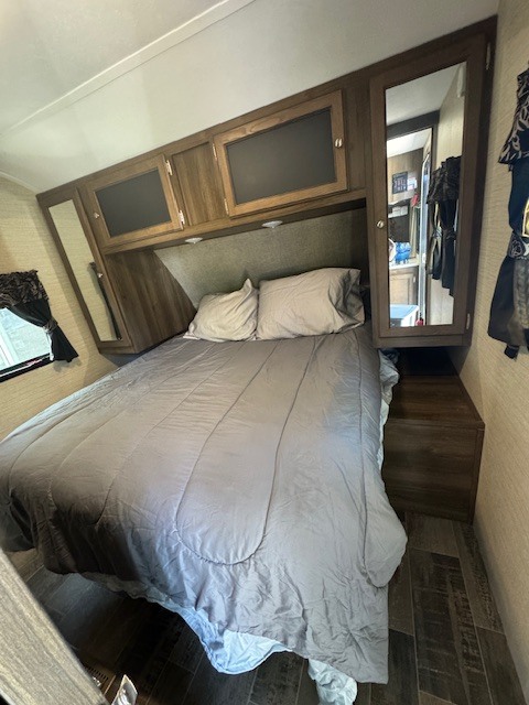 Cozy RV rental bedroom featuring a comfortable bed, overhead storage, and a mirrored closet for a comfortable journey.. Keystone RV Bullet Ultra Lite 2017