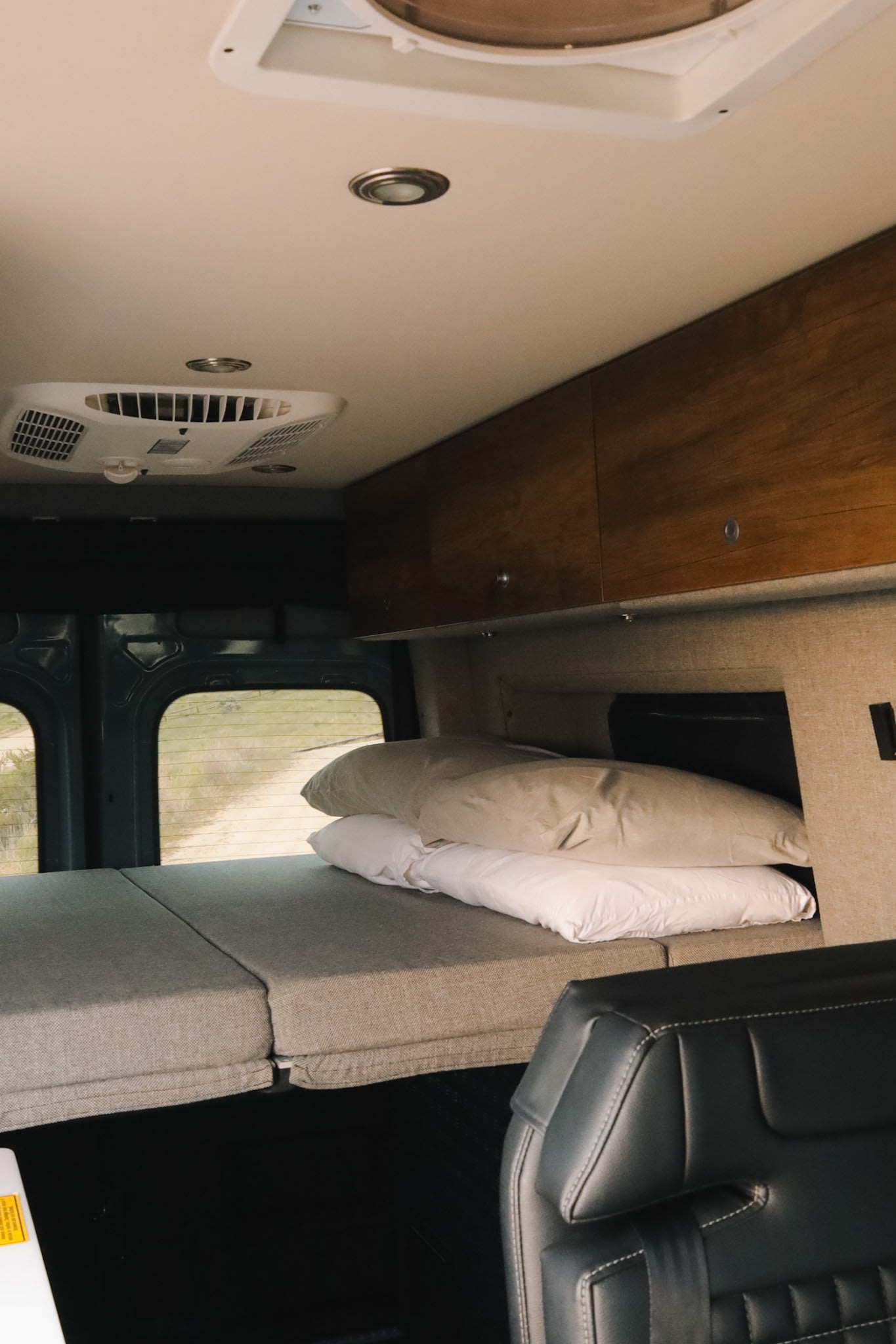 RV rental interior showing a comfortable sleeping area with pillows, overhead storage, and ceiling AC unit.. Mercedes-Benz Sprinter Storyteller 2020