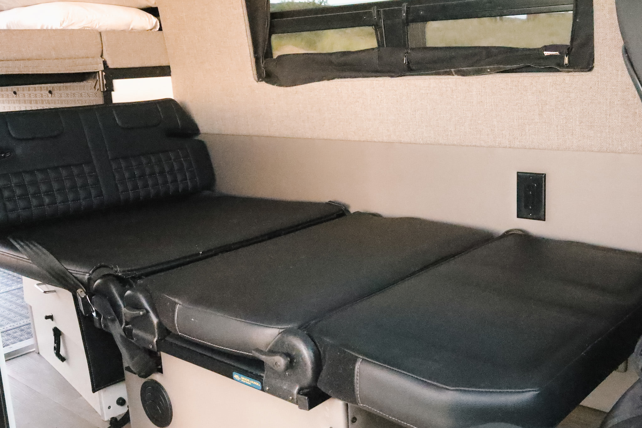 RV rental interior: convertible black leather seating with seatbelts, folds out to a bed.. Mercedes-Benz Sprinter Storyteller 2020