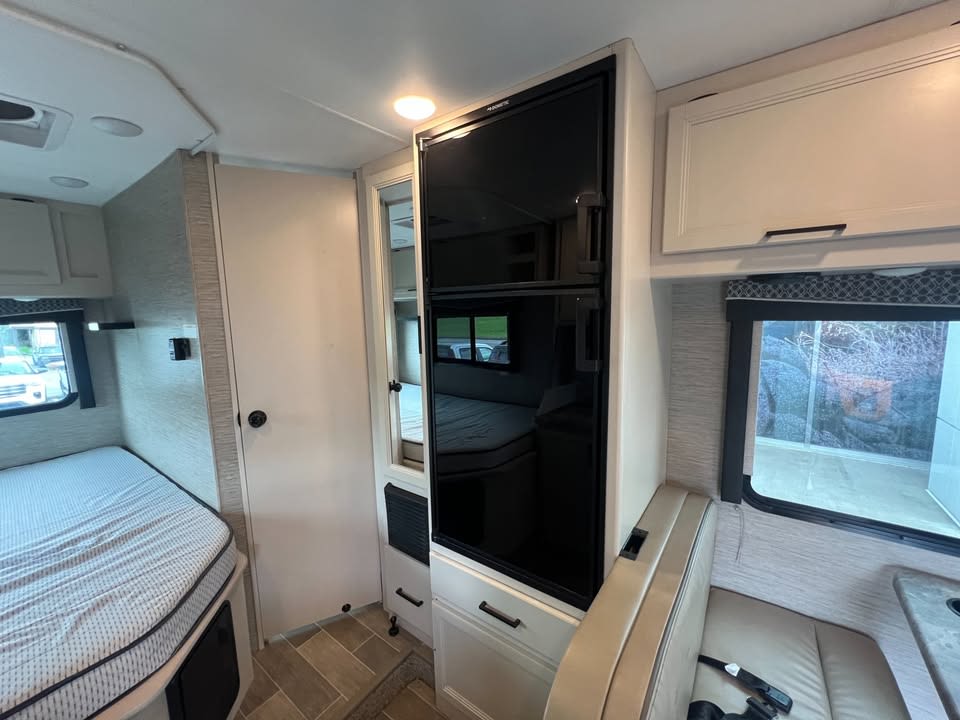 Inside an inviting RV rental, showcasing a comfortable bed, convenient Dometic fridge, and a cozy dinette for travelers.. Thor Motor Coach Chateau 2022