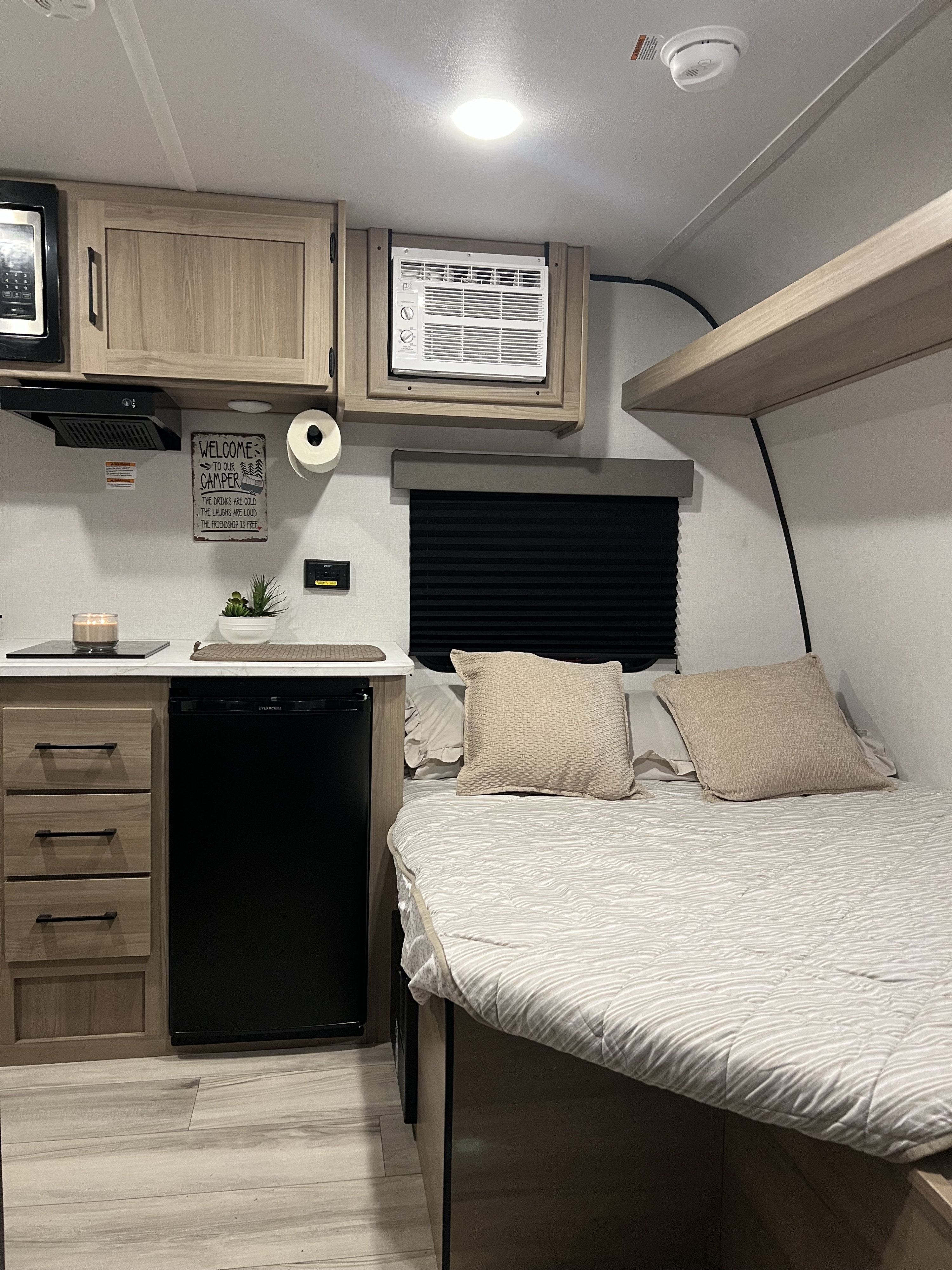 Inside a modern rv rental: bright kitchenette with microwave, fridge, bed with pillows. Ready for your cozy camping trip.. Keystone RV 13b 2026