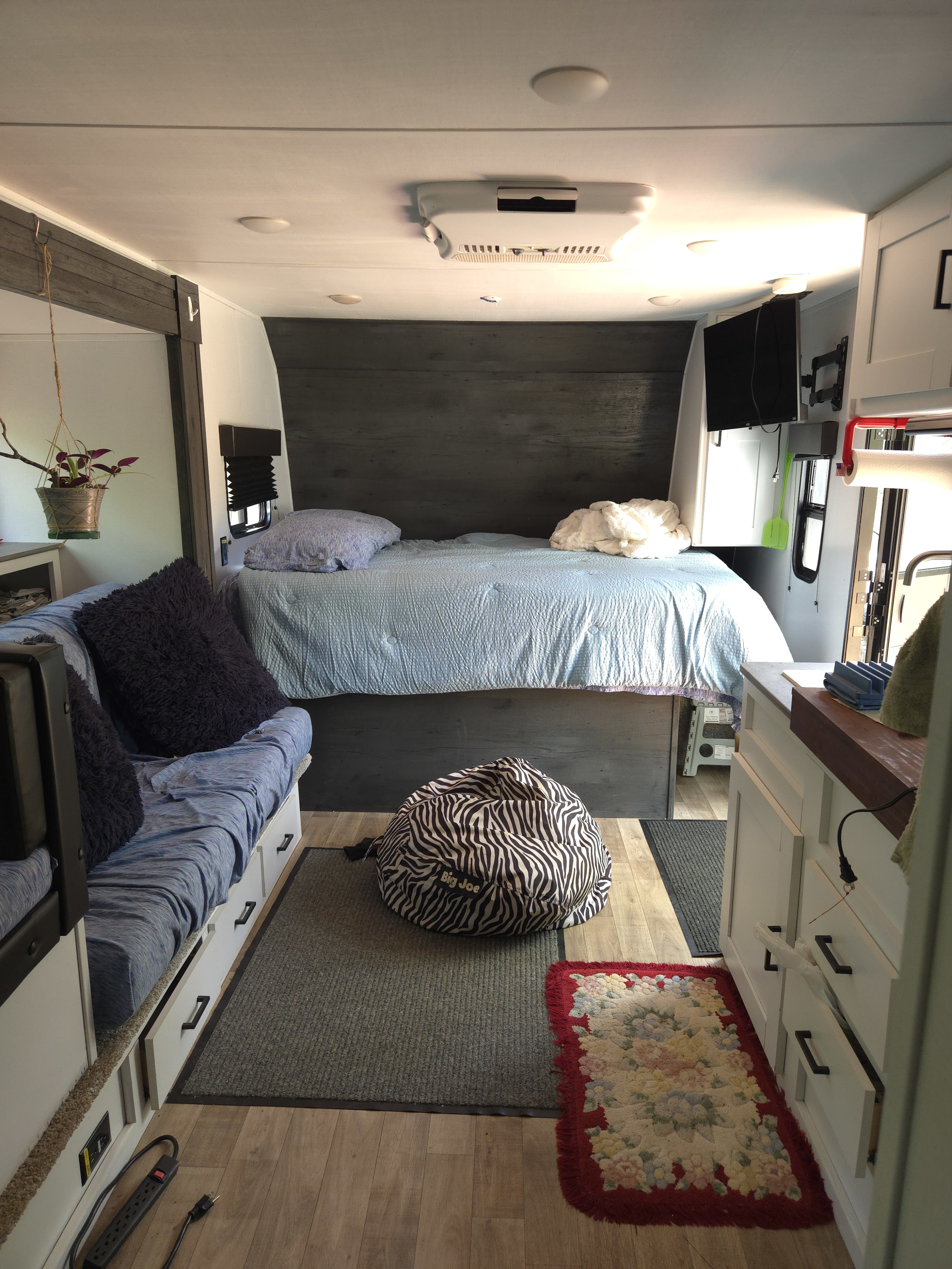 Comfortable rv rental interior: blue bed, sofa with drawers, compact kitchen counter, and bean bag chair for travel.. Keystone RV Hideout 2022