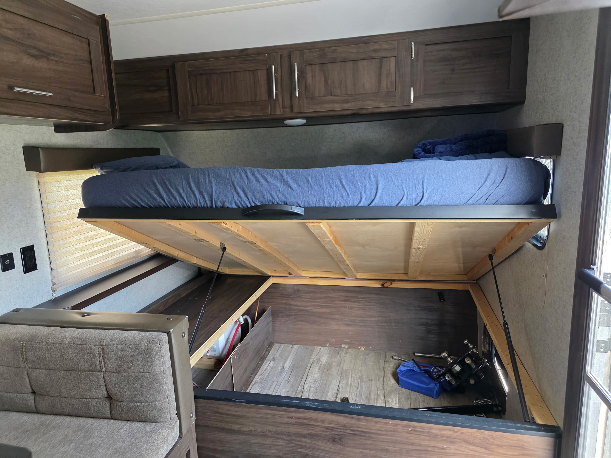 This rv rental features a lift-up bed revealing ample under-bed storage, with additional overhead cabinets visible.. Forest River Cherokee Wolf Pup 2018