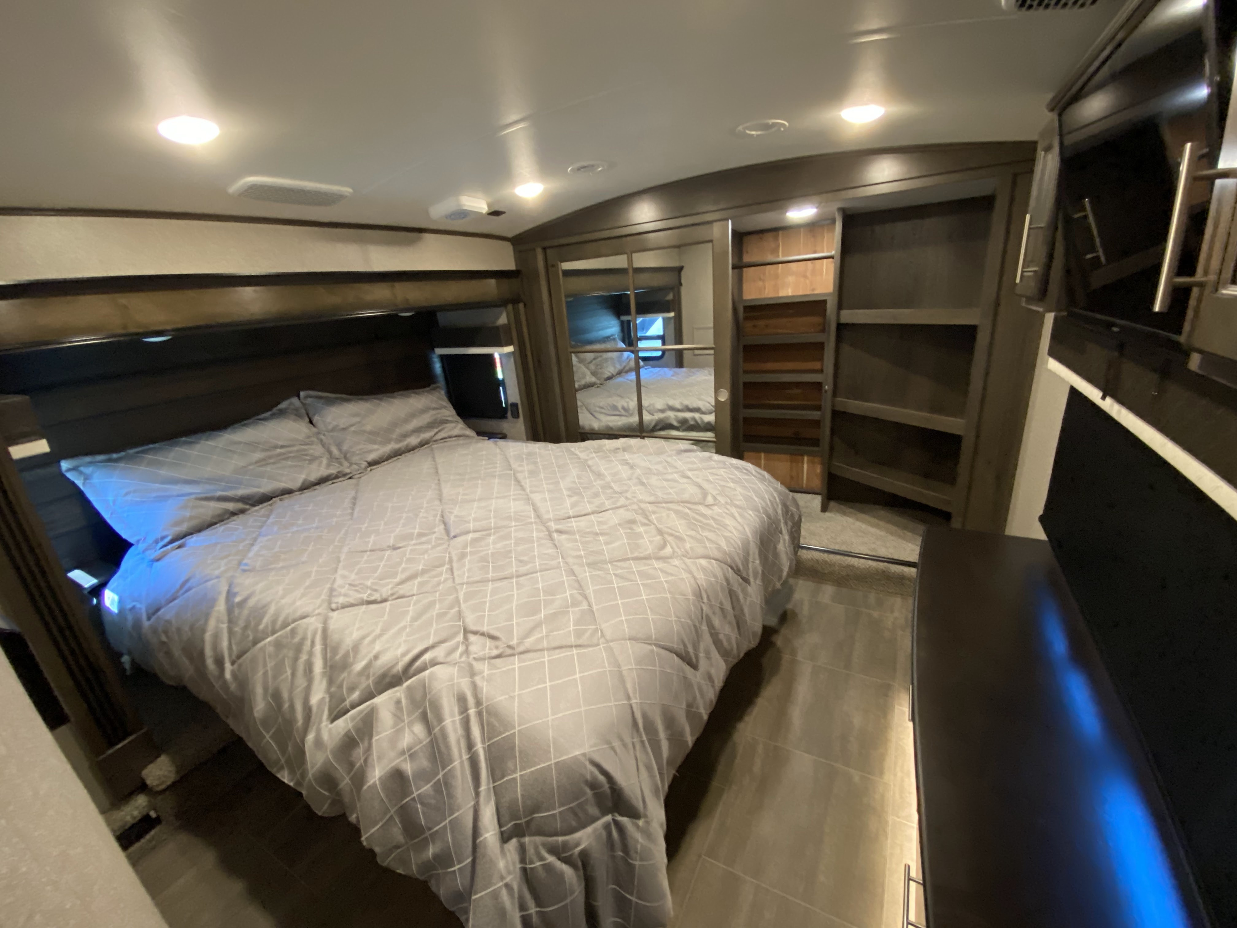 Enjoy a comfortable and spacious bedroom in this RV rental, featuring a cozy bed, modern lighting, and ample storage.. Jayco Pinnacle 2020
