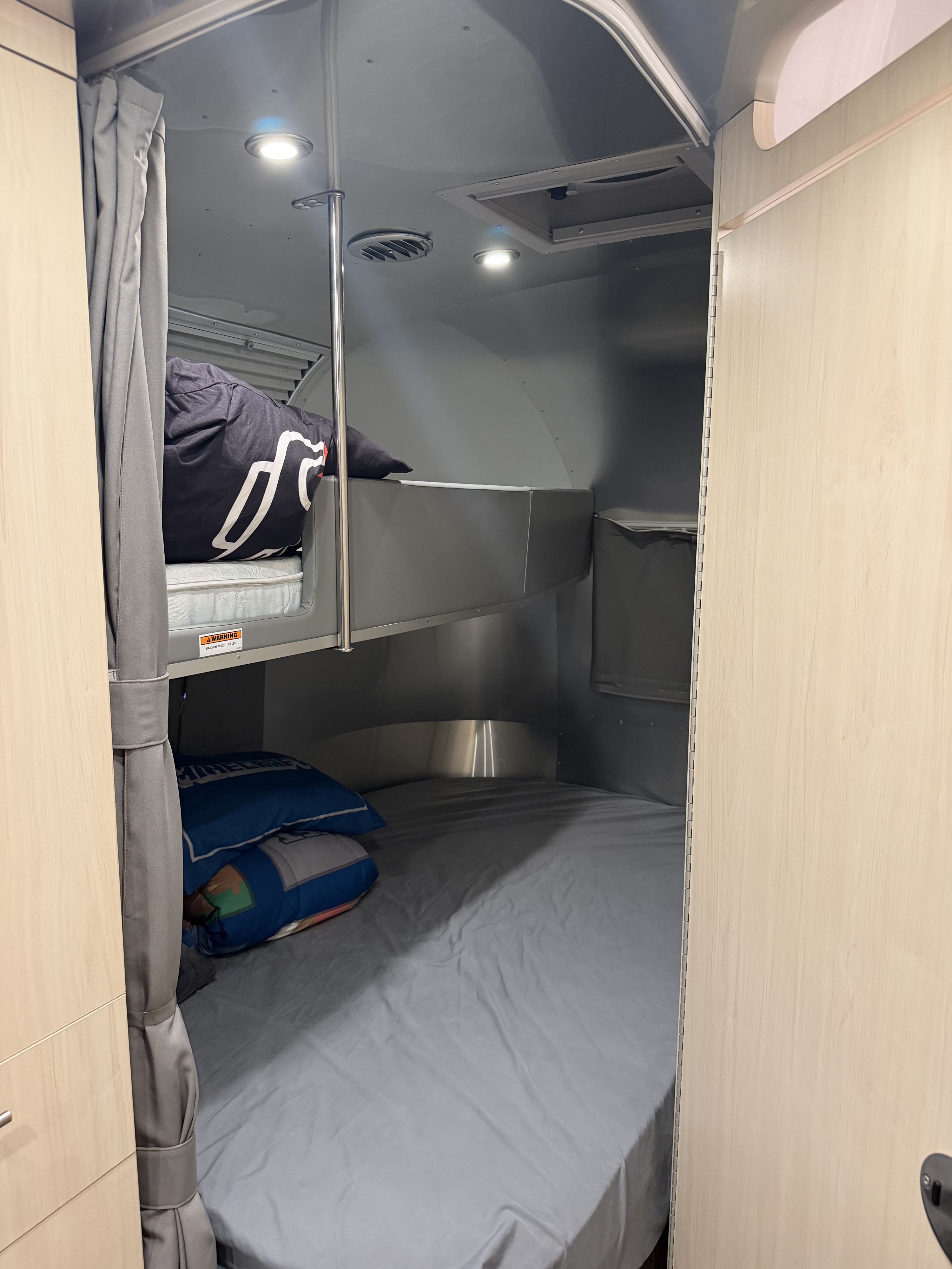 Cozy bunk beds in an RV rental, perfect for family travel. Features include lights, ventilation, and a maximum weight warning.. Airstream Flying Cloud 2022