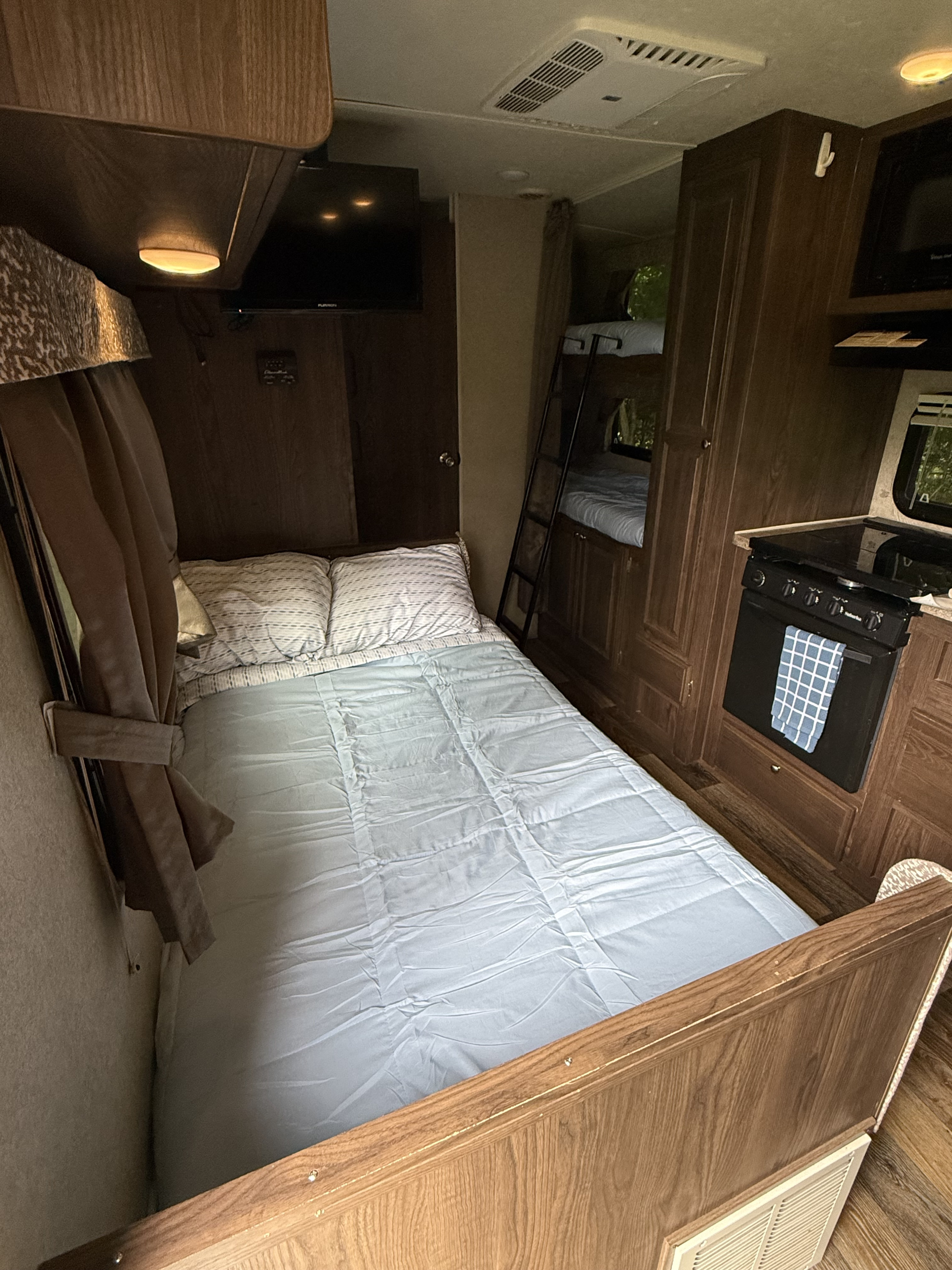 Cozy RV rental interior: main bed, bunk beds, TV, and a compact kitchen with a stove/oven.. Forest River Rockwood Mini Lite 2016