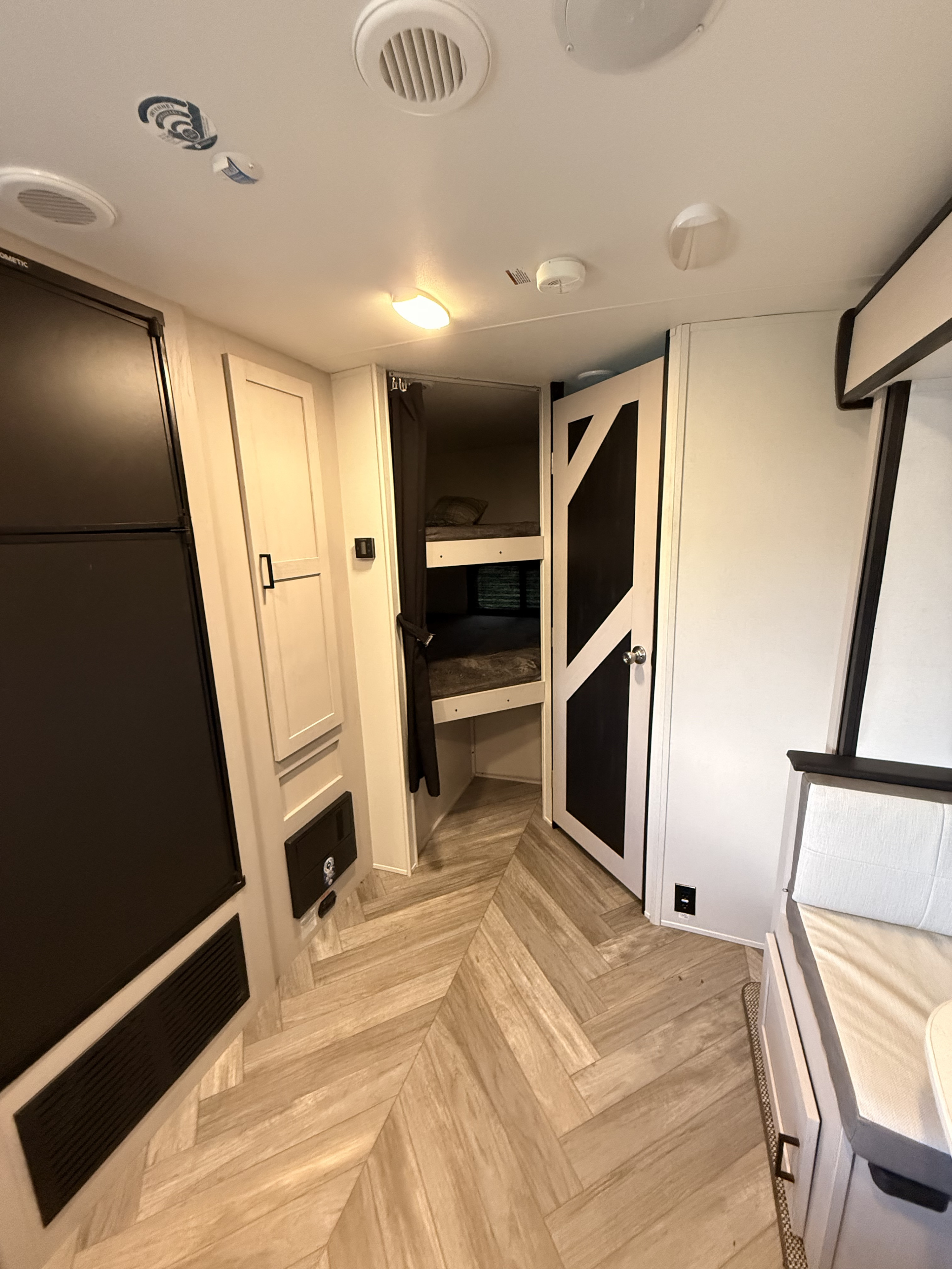 Cozy RV rental interior with bunk beds, fridge, dinette, and stylish herringbone flooring.. Heartland RVs Mallard 2024