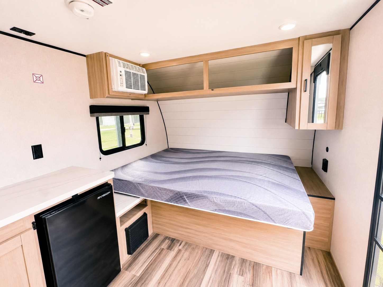 RV rental interior: Bed with gray mattress, AC, mini-fridge, and light wood storage cabinets for comfortable travel.. Highland Ridge RV Colt CTR 2026