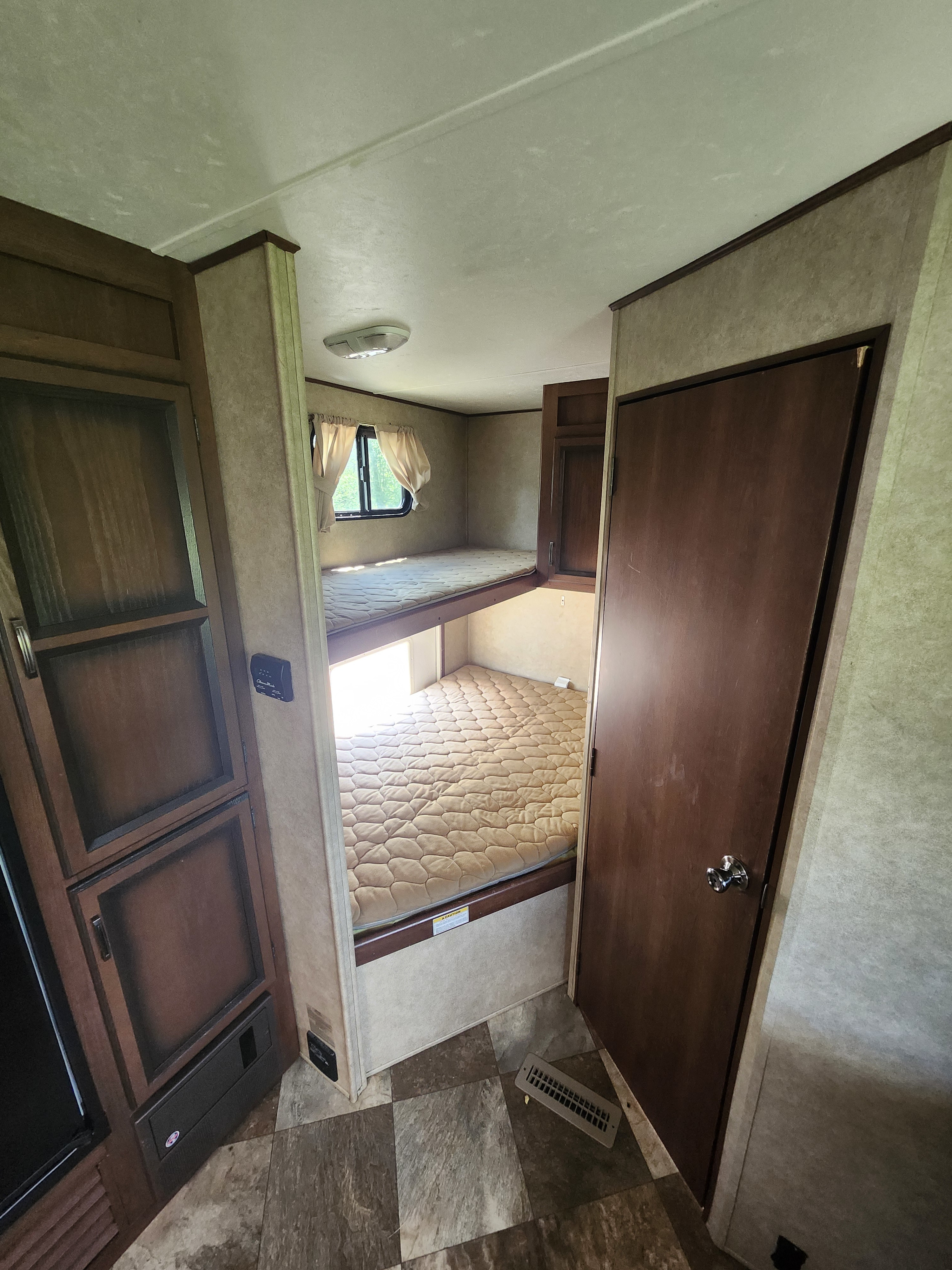 Cozy RV rental interior with bunk beds, a storage cabinet, and a door, ideal for family travel in a camper.. 4V0TC2620FJ005216 Crossroads 2015