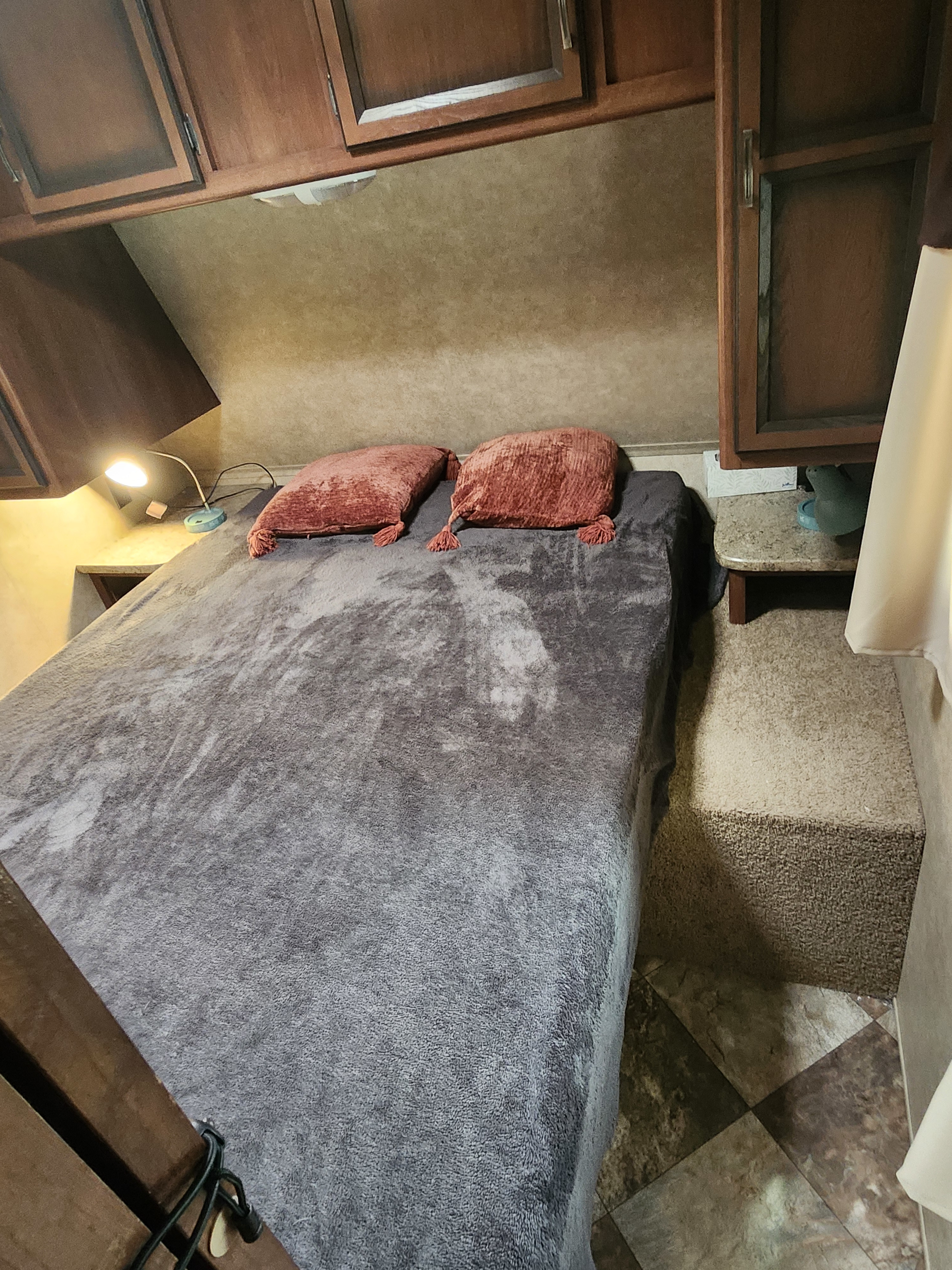 Compact RV rental bedroom with a comfy bed, two pillows, overhead storage cabinets, and functional bedside lighting.. 4V0TC2620FJ005216 Crossroads 2015
