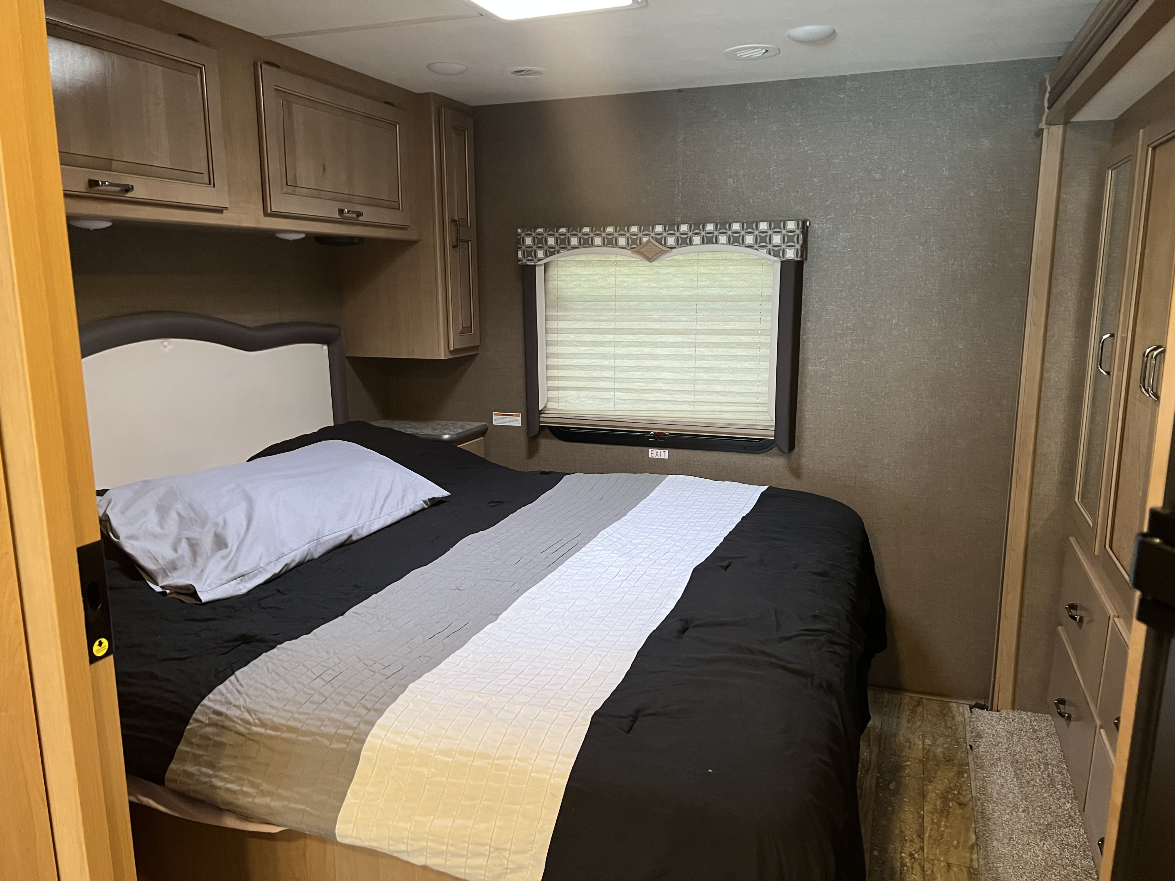 RV rental bedroom with bed, overhead cabinets, and window. Comfortable and compact interior space.. Thor Hurricane 2019
