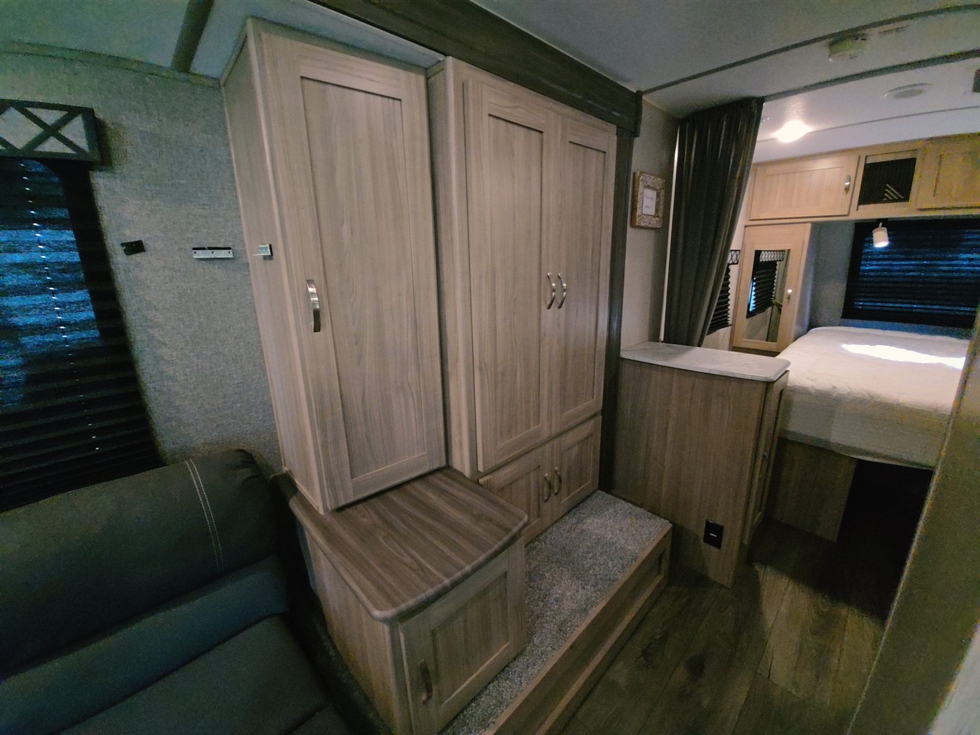 RV rental interior: bedroom with bed, ample storage in wood wardrobes, and cozy living area seating. Ideal for travel comfort.. Coachmen Freedom Express 2021