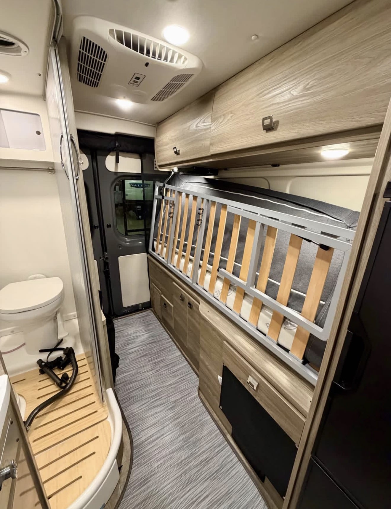 This rv rental's compact interior features a fold-away bed, integrated toilet/shower, overhead AC, and modern design.. Winnebago Travato 2023