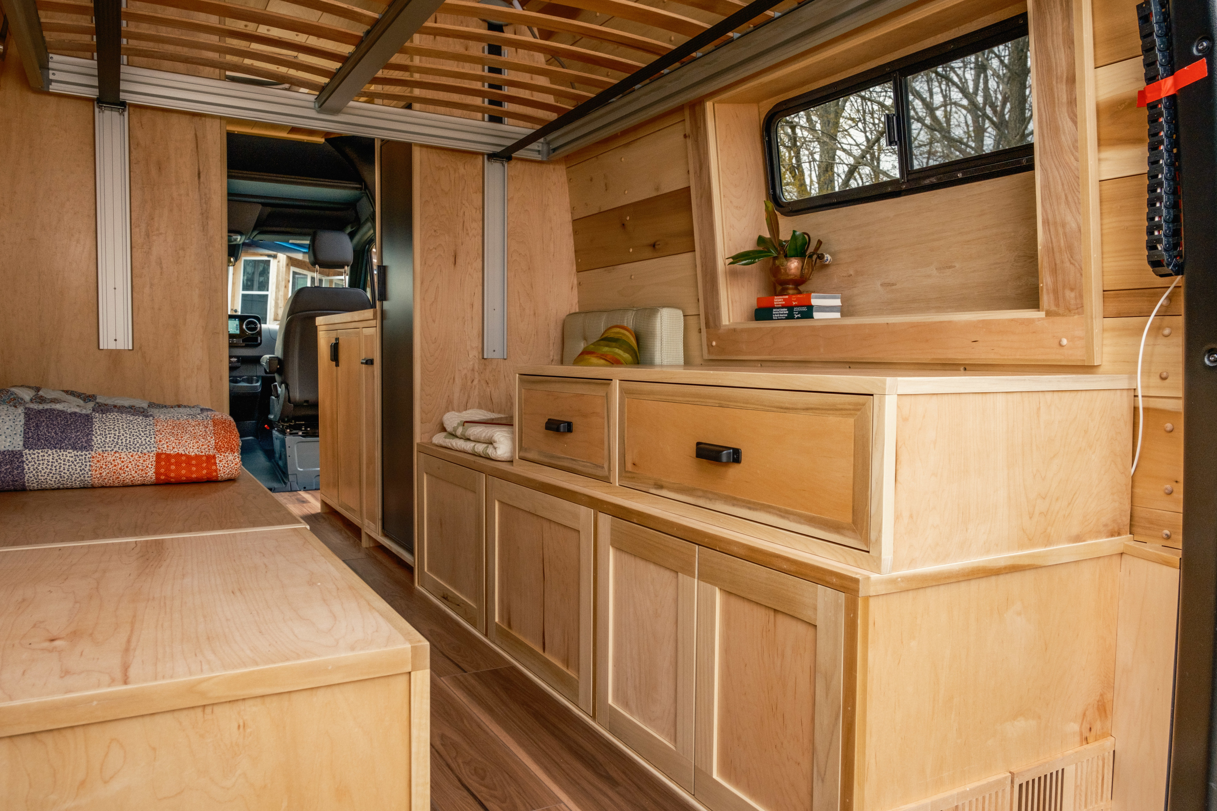 Explore this inviting RV rental with a custom light wood interior, featuring handcrafted cabinets, drawers, and a comfy bed.. Mercedes-Benz Sprinter 2024