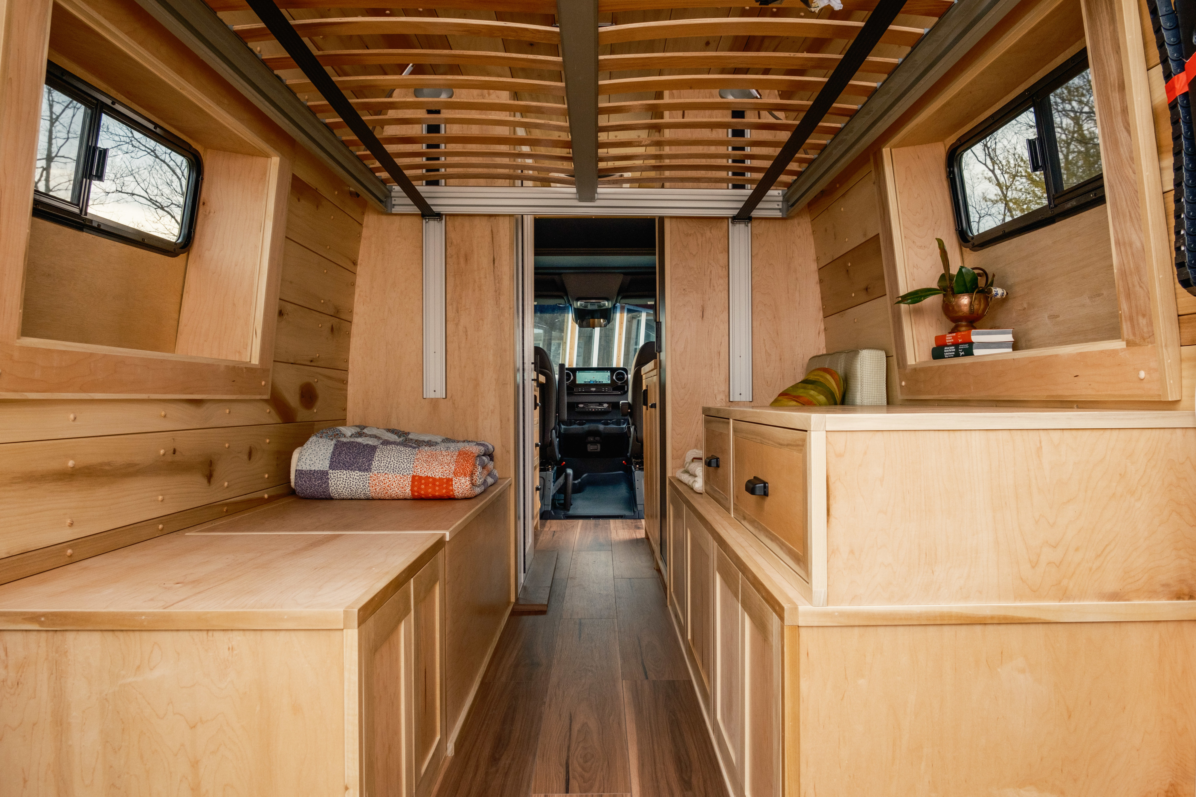 Step inside this cozy rv rental camper van, featuring a beautiful wooden interior with built-in storage, sleeping areas, and a view to the cockpit.. Mercedes-Benz Sprinter 2024